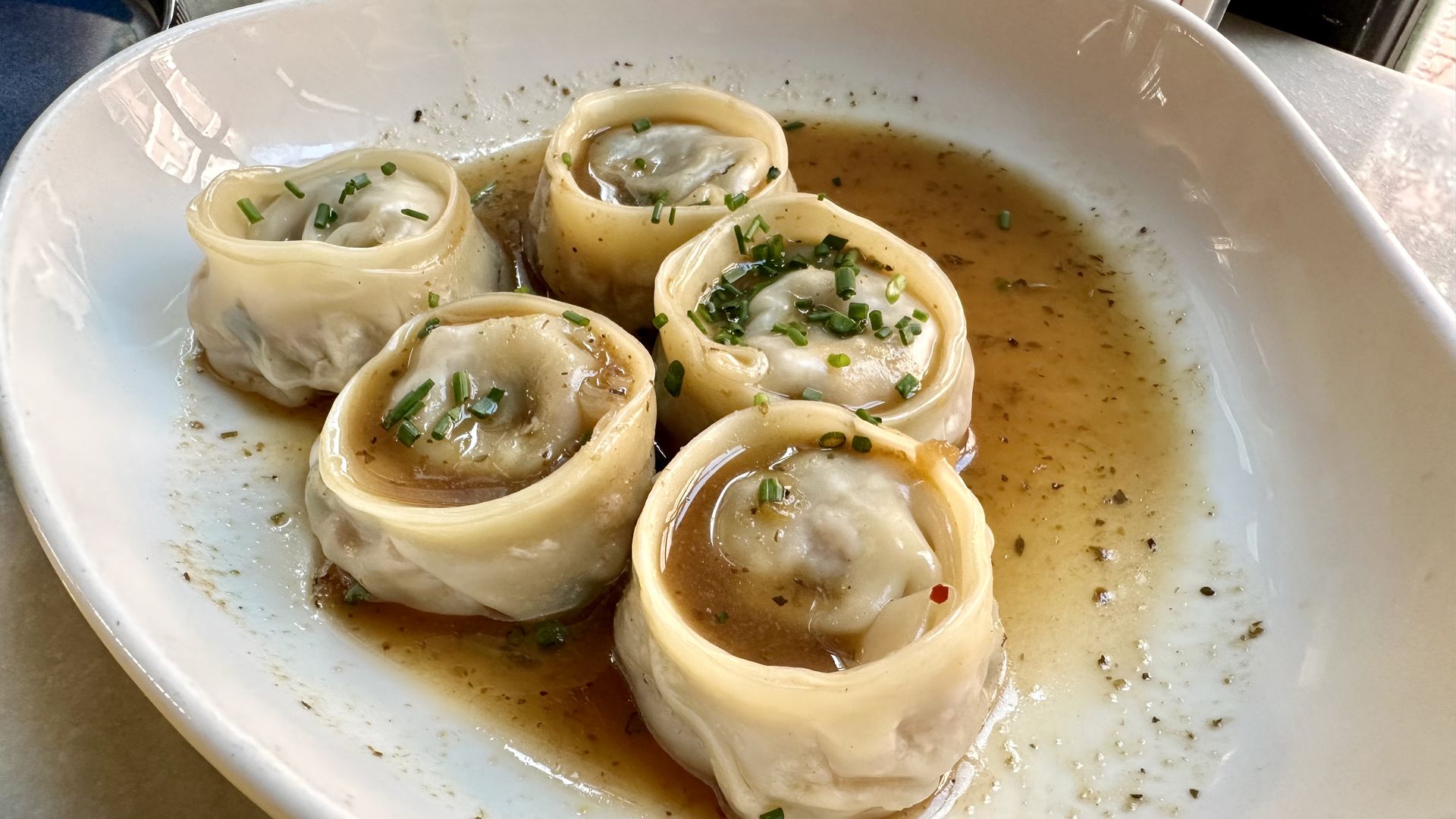 Photo shows five roundish dumplings in a bowl with broth.