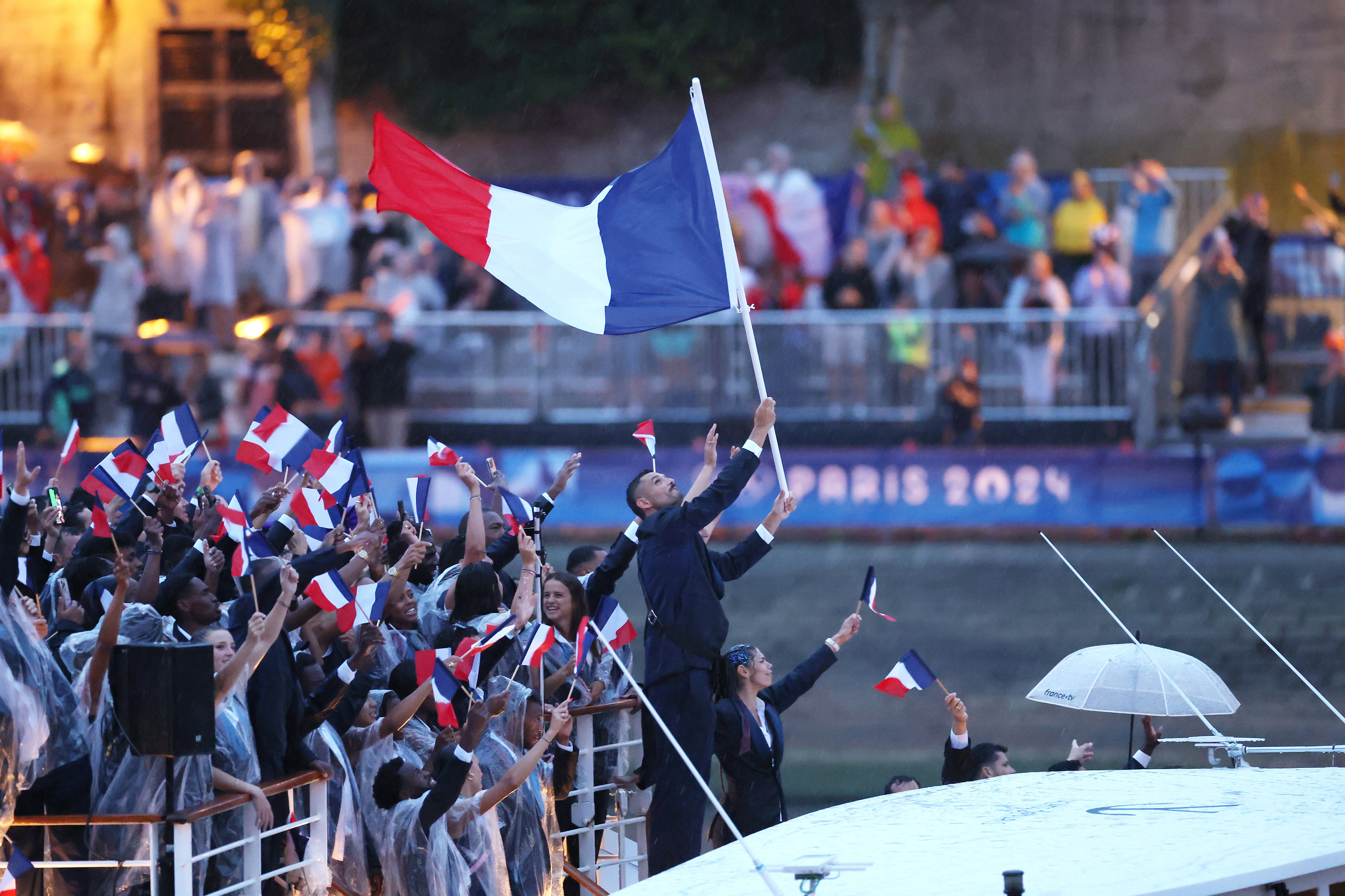 Florent Manaudou and Melina Robert-Michon, flagbearers of Team France, are seen waving their flag on a boat with team mates along the River Seine during the opening ceremony of the Olympic Games Paris 2024 on July 26, 2024 in Paris, France. (Photo by Alex Davidson/Getty Images)