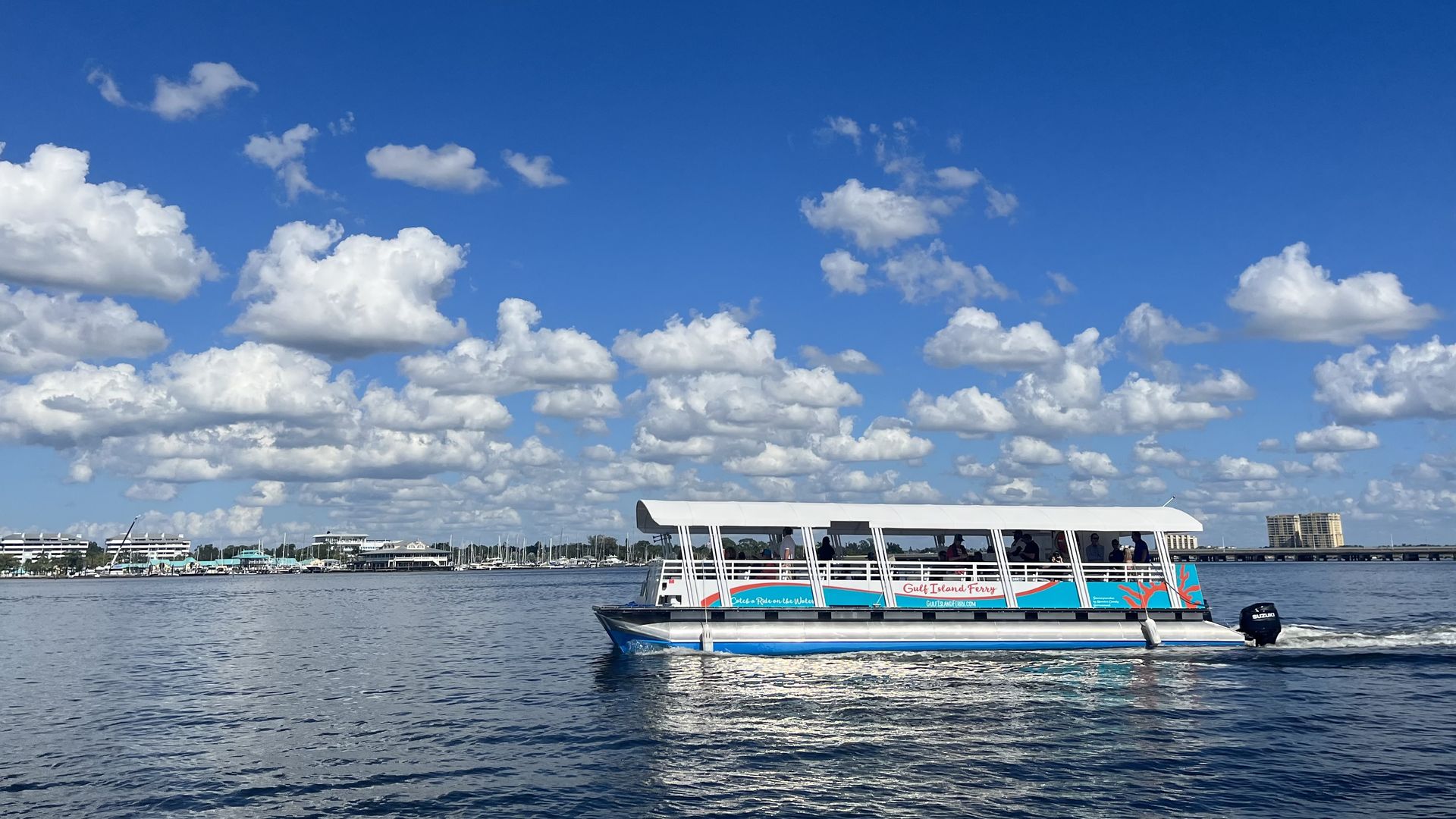 A catamaran with "Gulf Island Ferry" painted in orange on the side cuts through water. 
