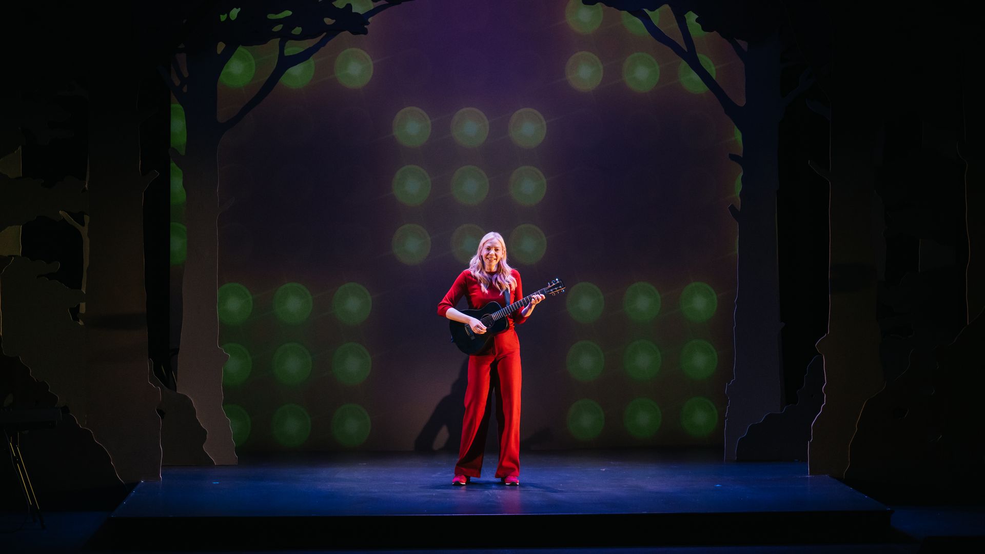 The actor Riki Lindhome standing on a stage while performing her one-woman show "Dead Inside."