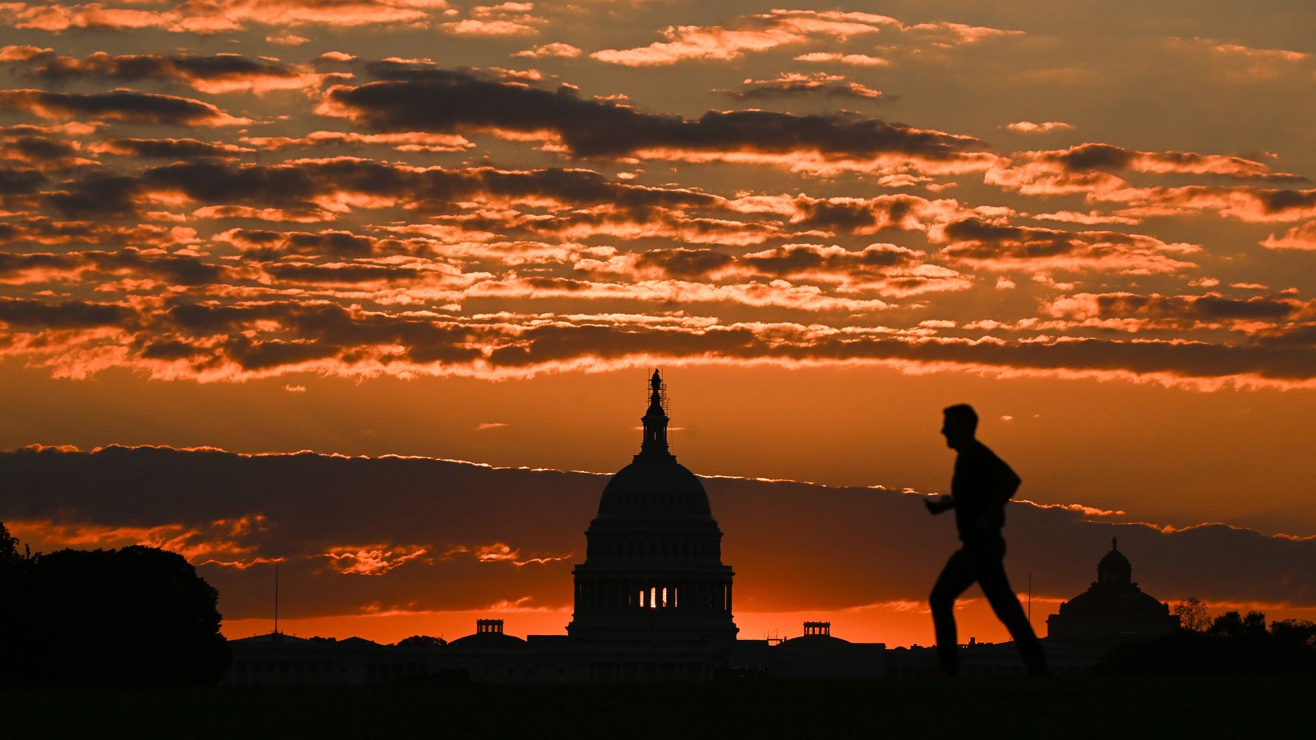 The Capitol Building in an ominous orange sunset with a man running 