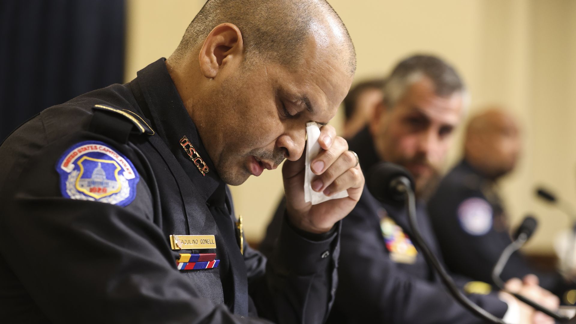 Photo of a police officer in uniform as he wipes his eyes with a tissue
