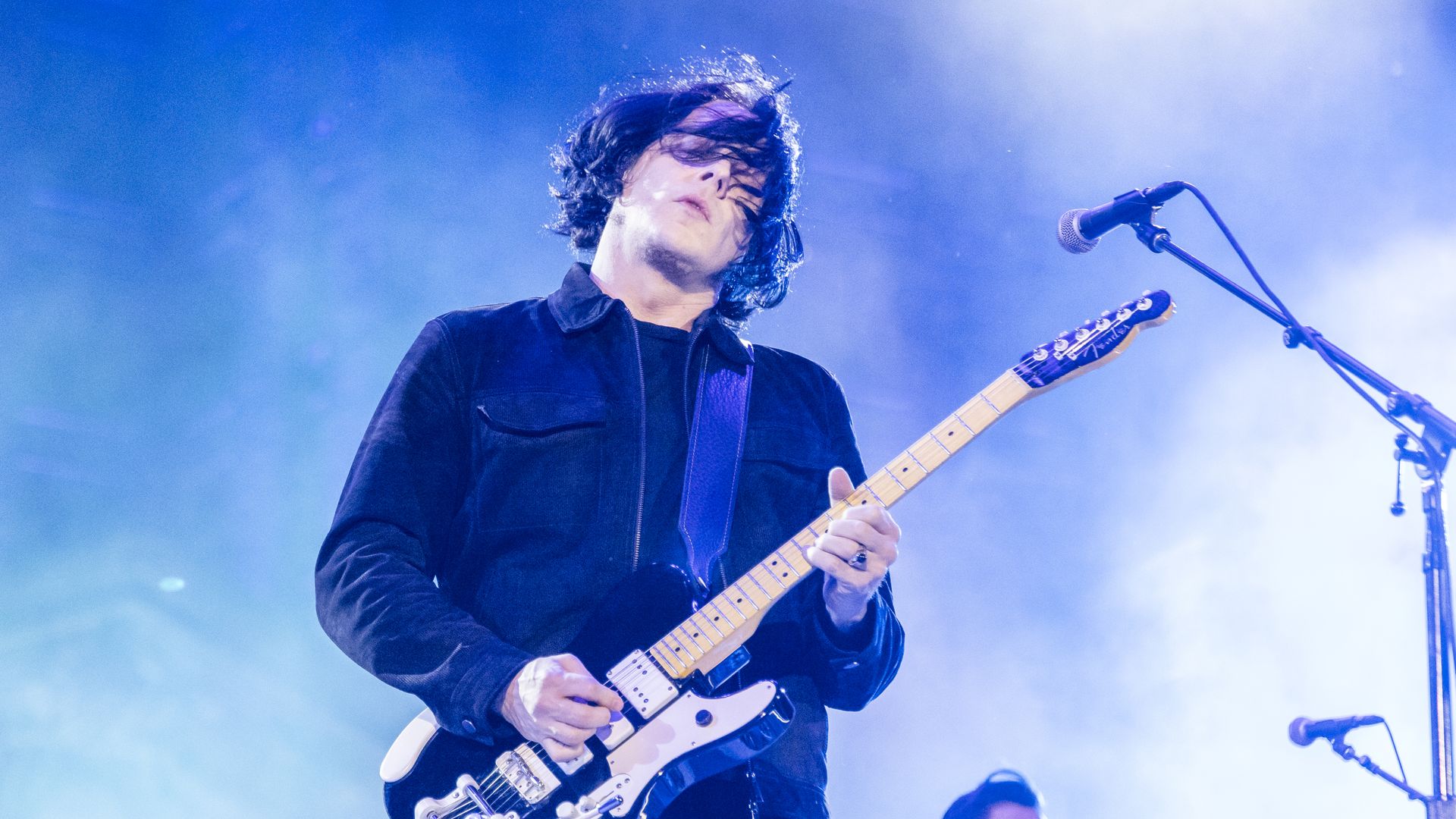 Musician Jack White performs on stage with his guitar.
