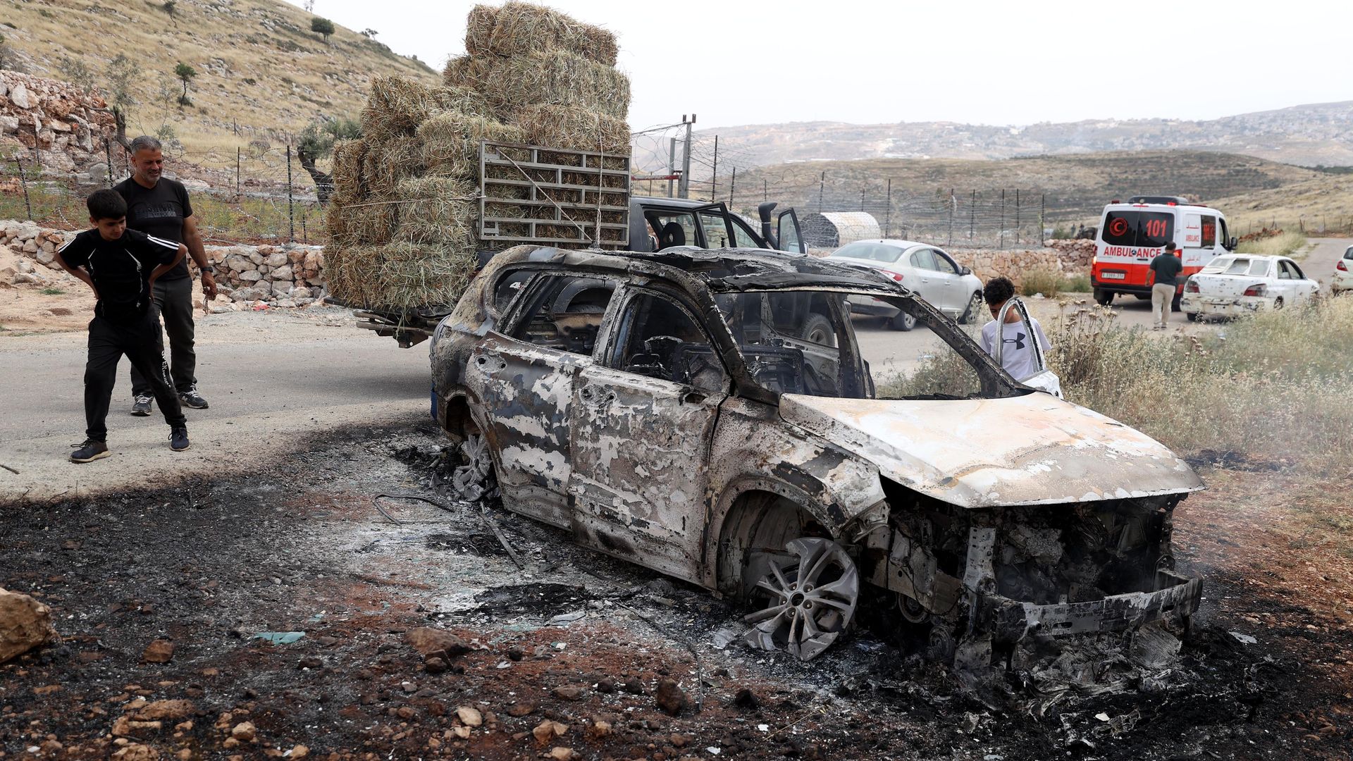 Palestinians observe the burnt car at the town of Mugayyir in Ramallah, West Bank on May 26, 2023. 