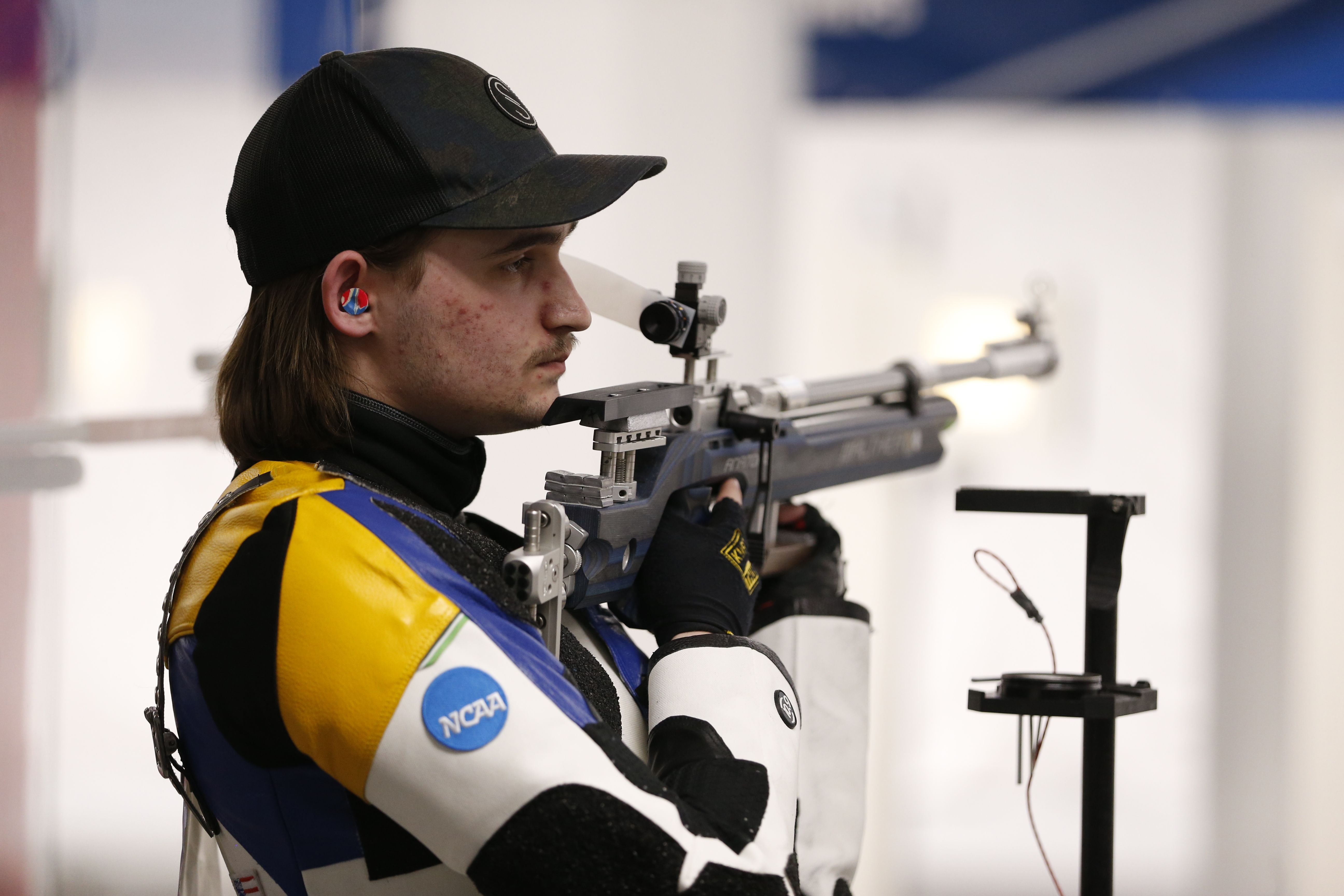A man in a ball cap holds a long rifle in his hands. 