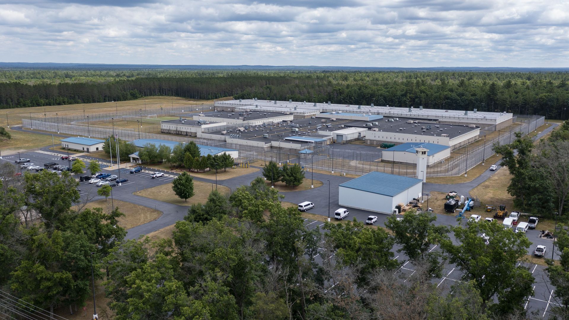 A drone overview of a large fenced off facility in the middle of a forest