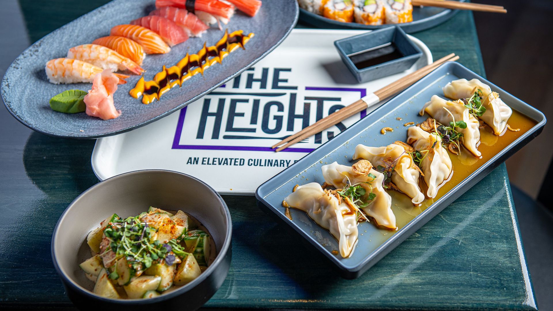 A blue table with dumplings, cucumber salad and sushi from Doki Doki Sushi 