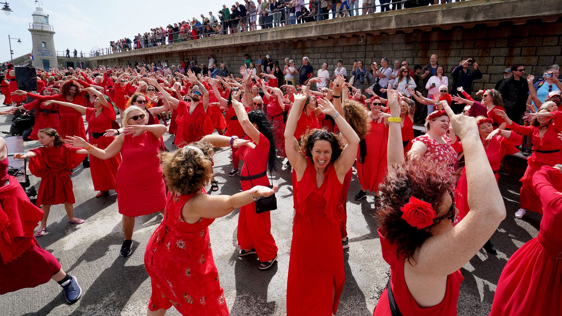 A photo of a large group of women all wearing red dresses dancing 