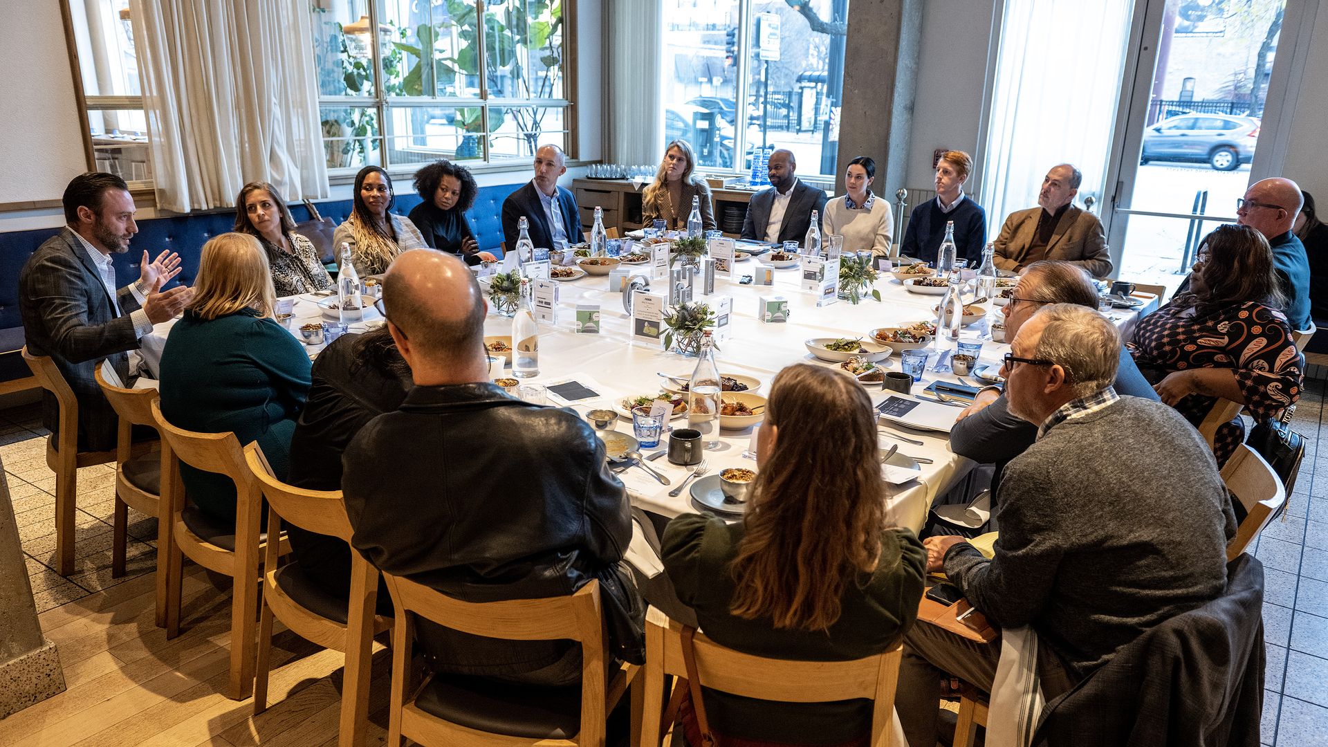 Attendees sitting around a square table eating breakfast.