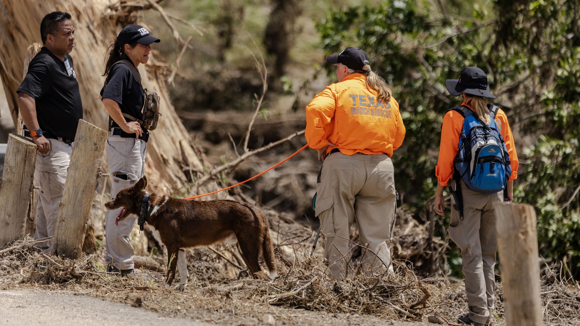 A search and rescue team with a dog. One woman's bright orange jacket says "Texas search and rescue."