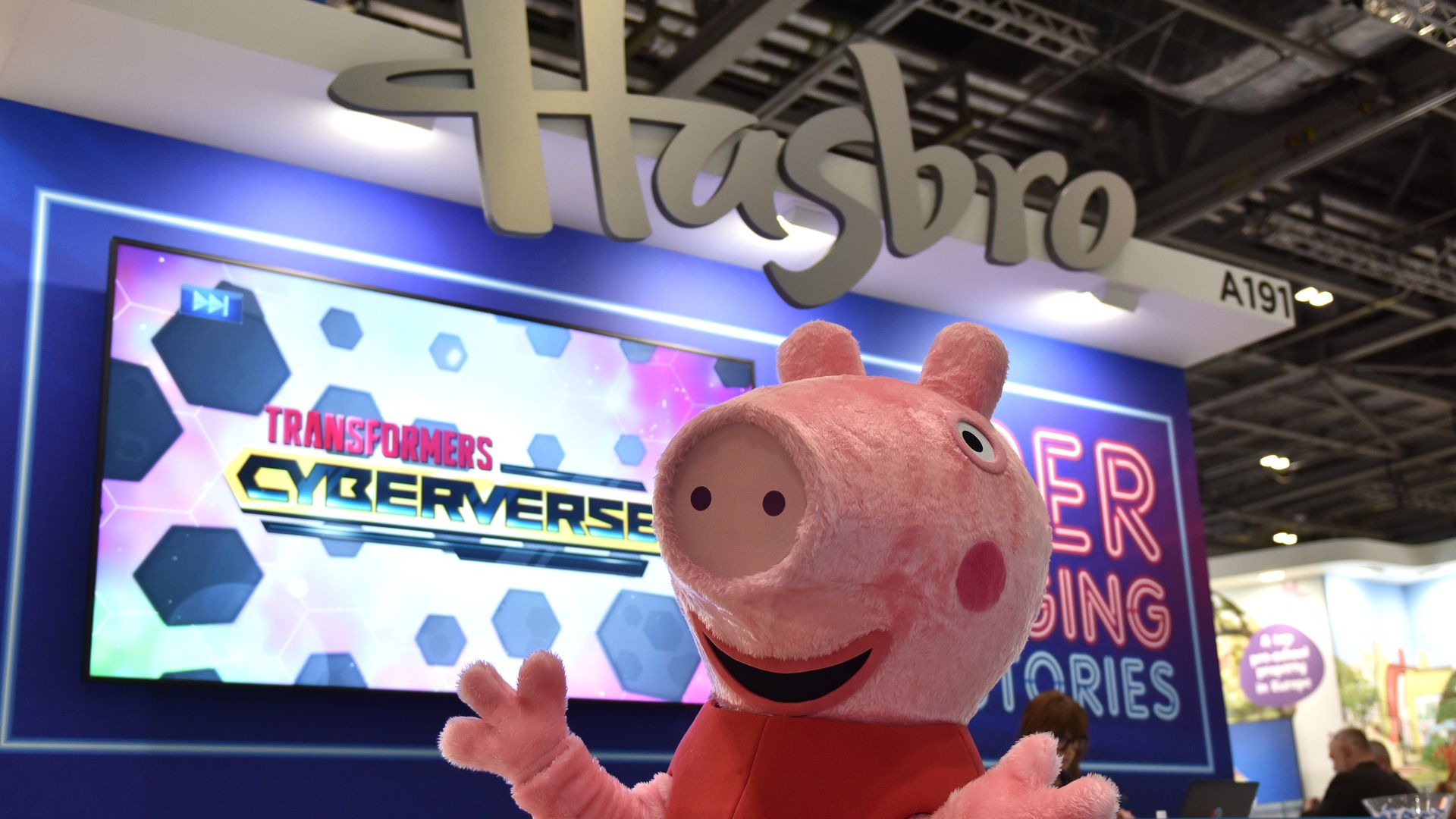 Animated character Peppa Pig appears in front of Hasbro's booth in a convention hall.