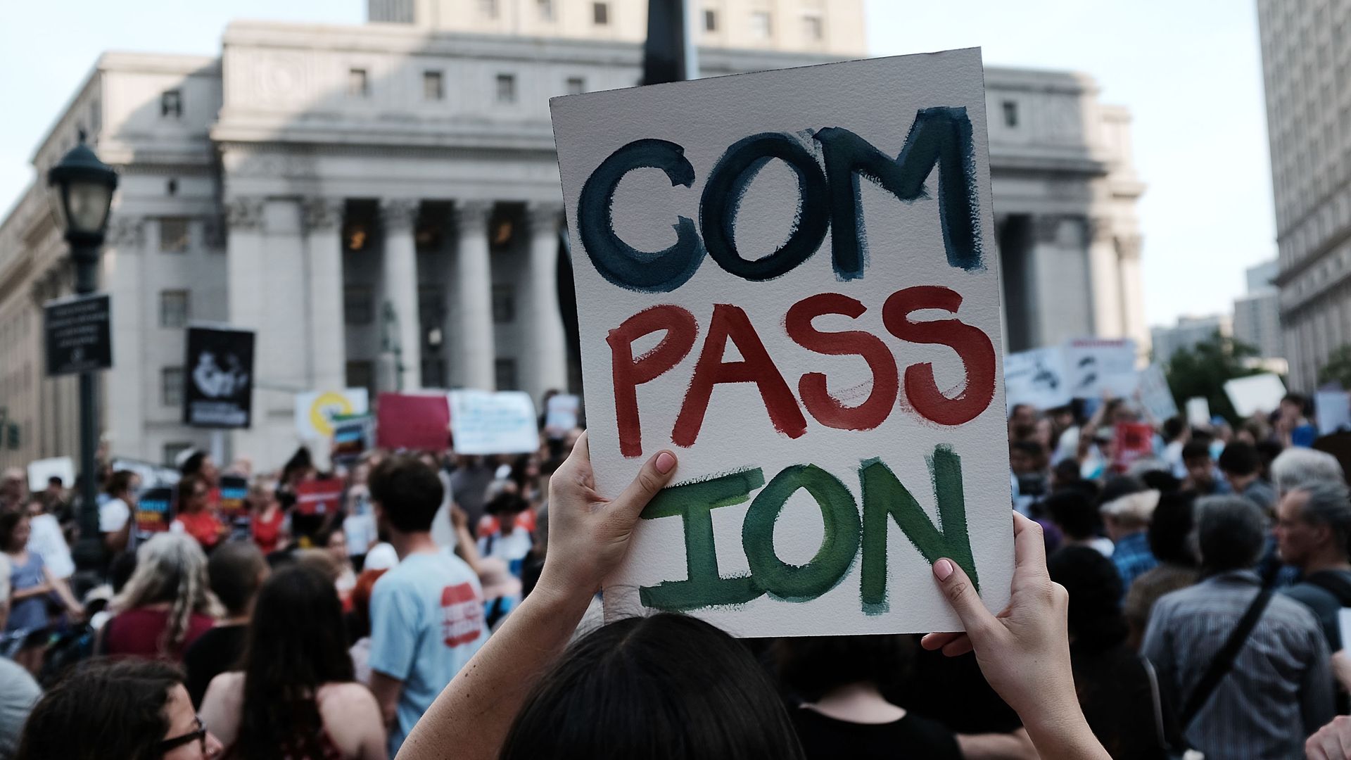 Protester holds sign reading "Compassion"