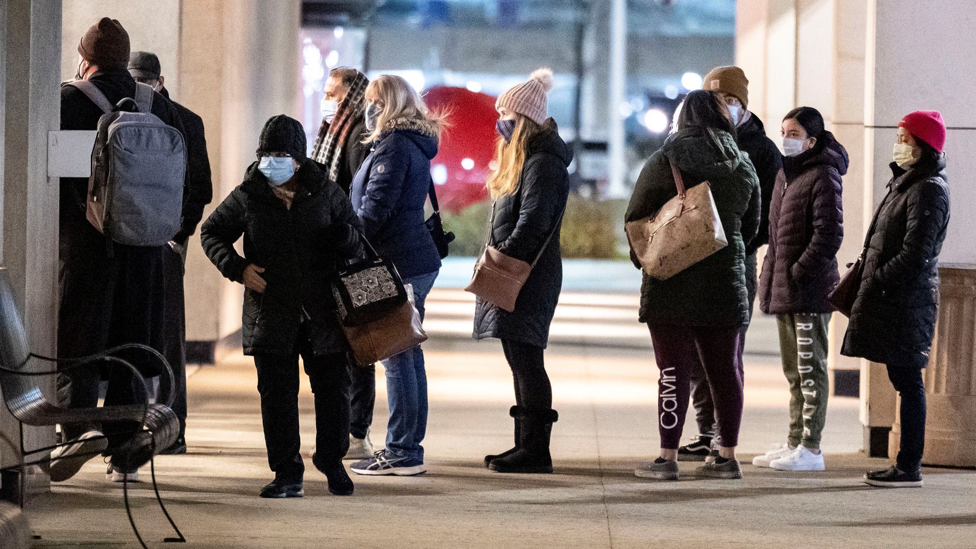 Image of people waiting in line at a store with masks on. 
