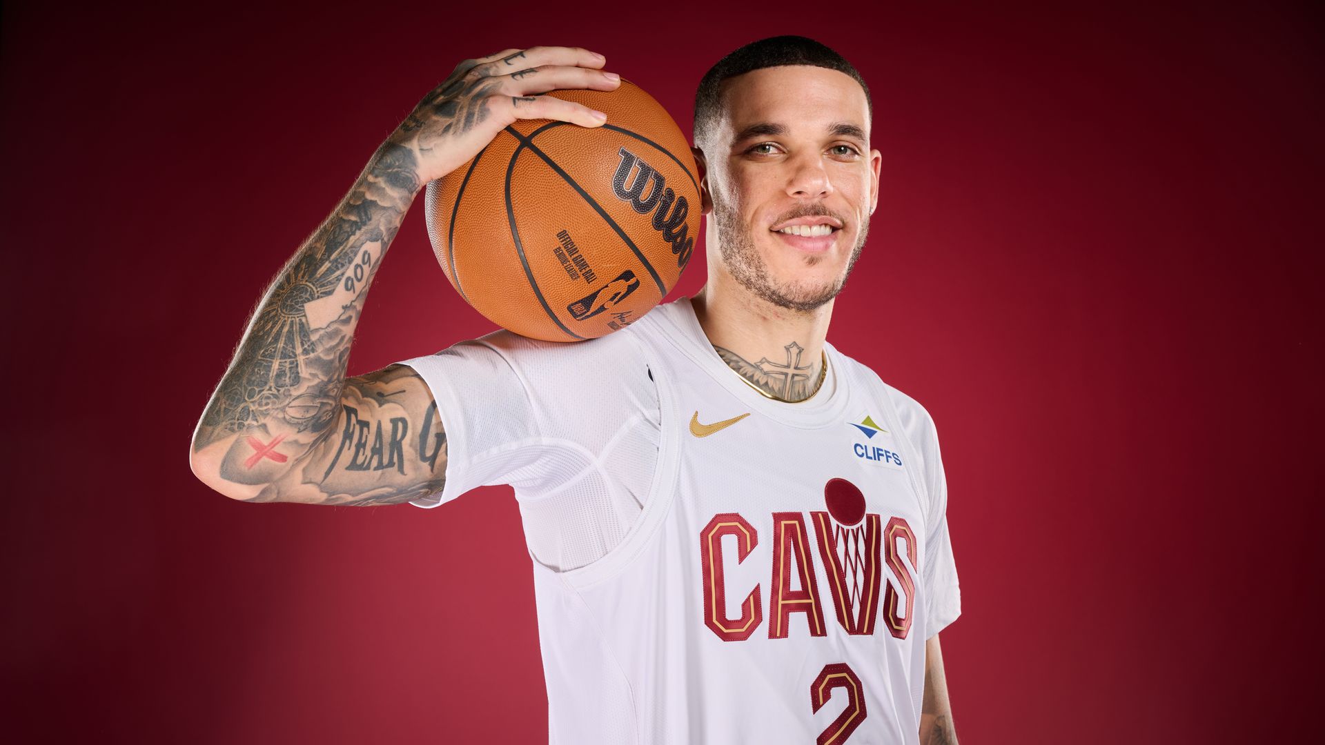 Photo of basketball player in white jersey on red background holding bball up on shoulder