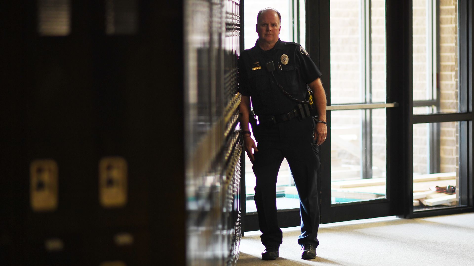 A police officer leans on school lockers.