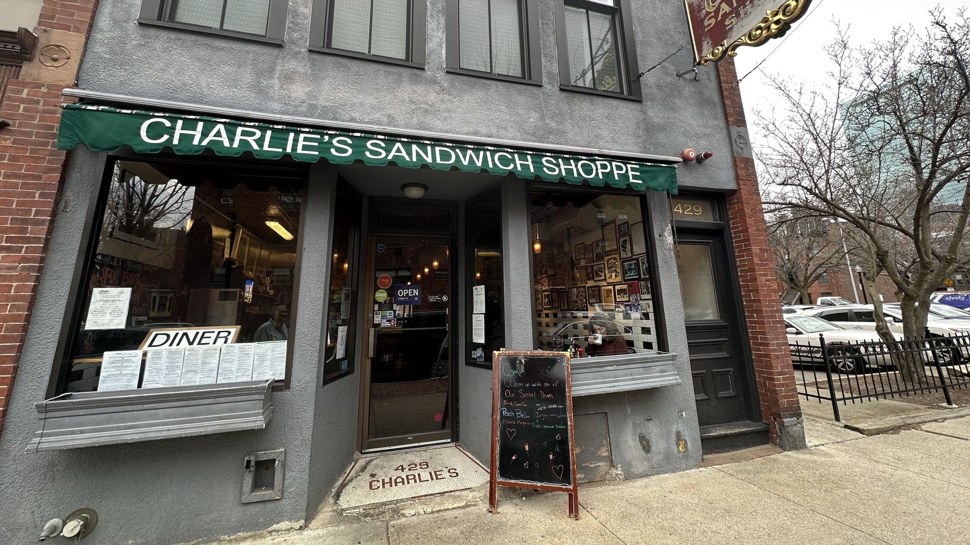 The front of Charlie's Sandwich Shoppe in the daytime gives you a clear view of the red sign and the green banner at the entrance.