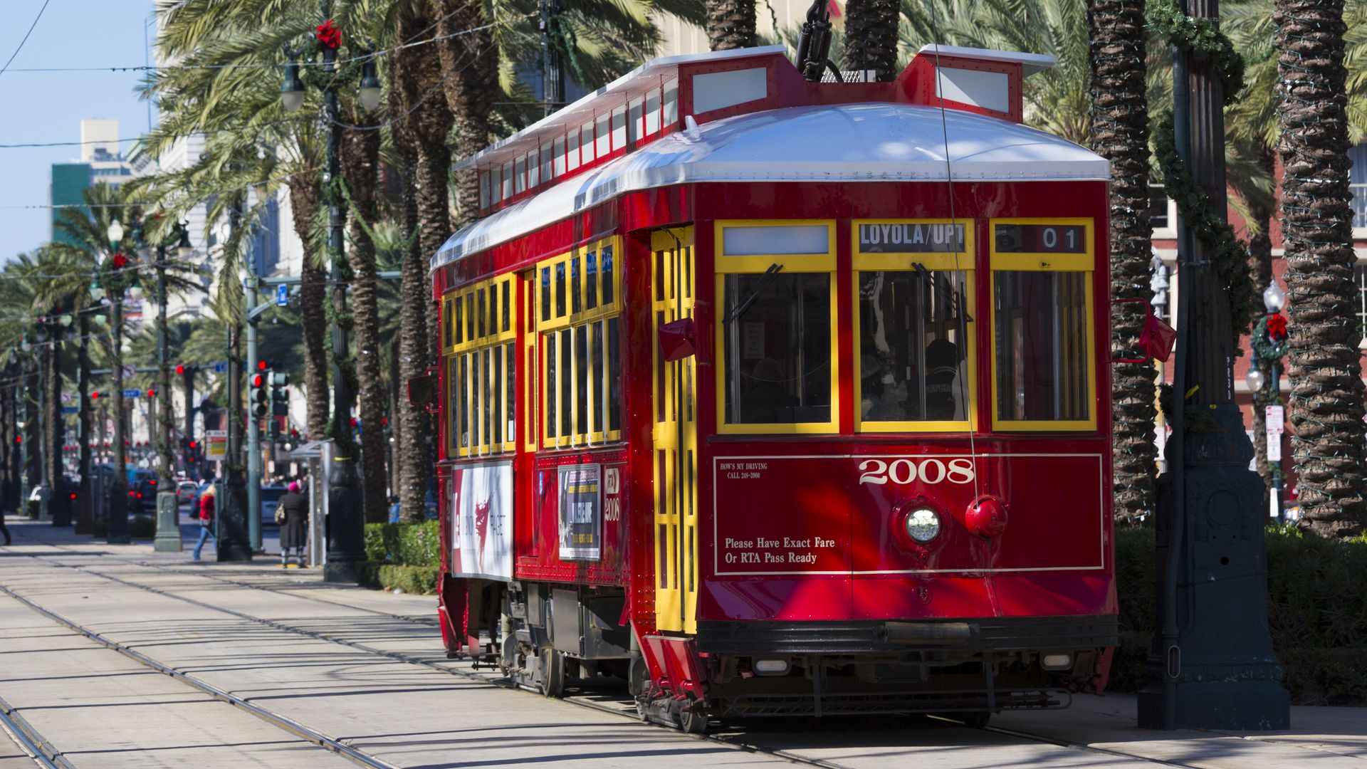A red streetcar is spotted rolling down the neutral ground of Canal Street.