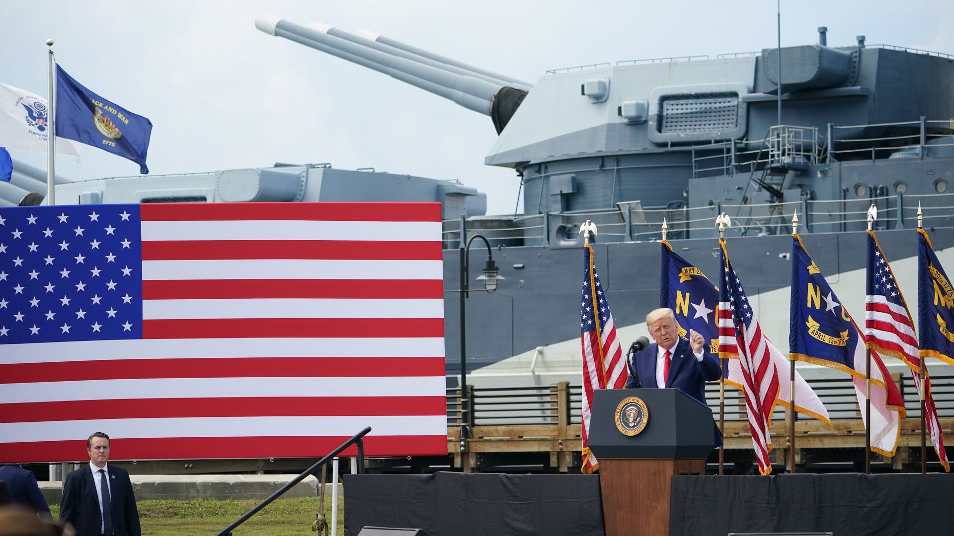 Trump stands in front of a row of American flags