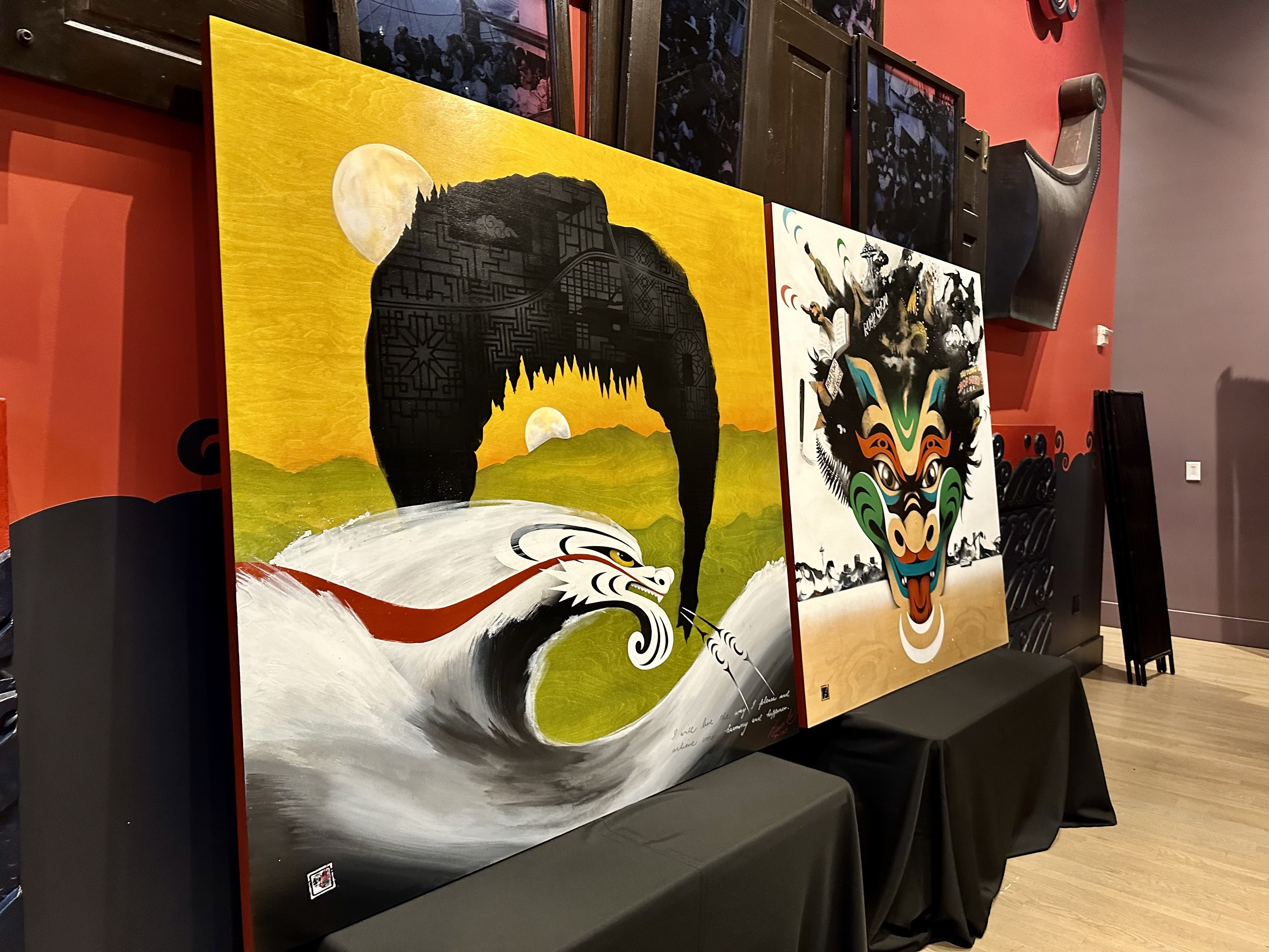 One mural panel shows Bruce Lee's hair framing a Coast Salish dragon, with a landcape in the background. The other panel is a dragon with elements relating to Seattle and Bruce Lee painted around the dragon's head.