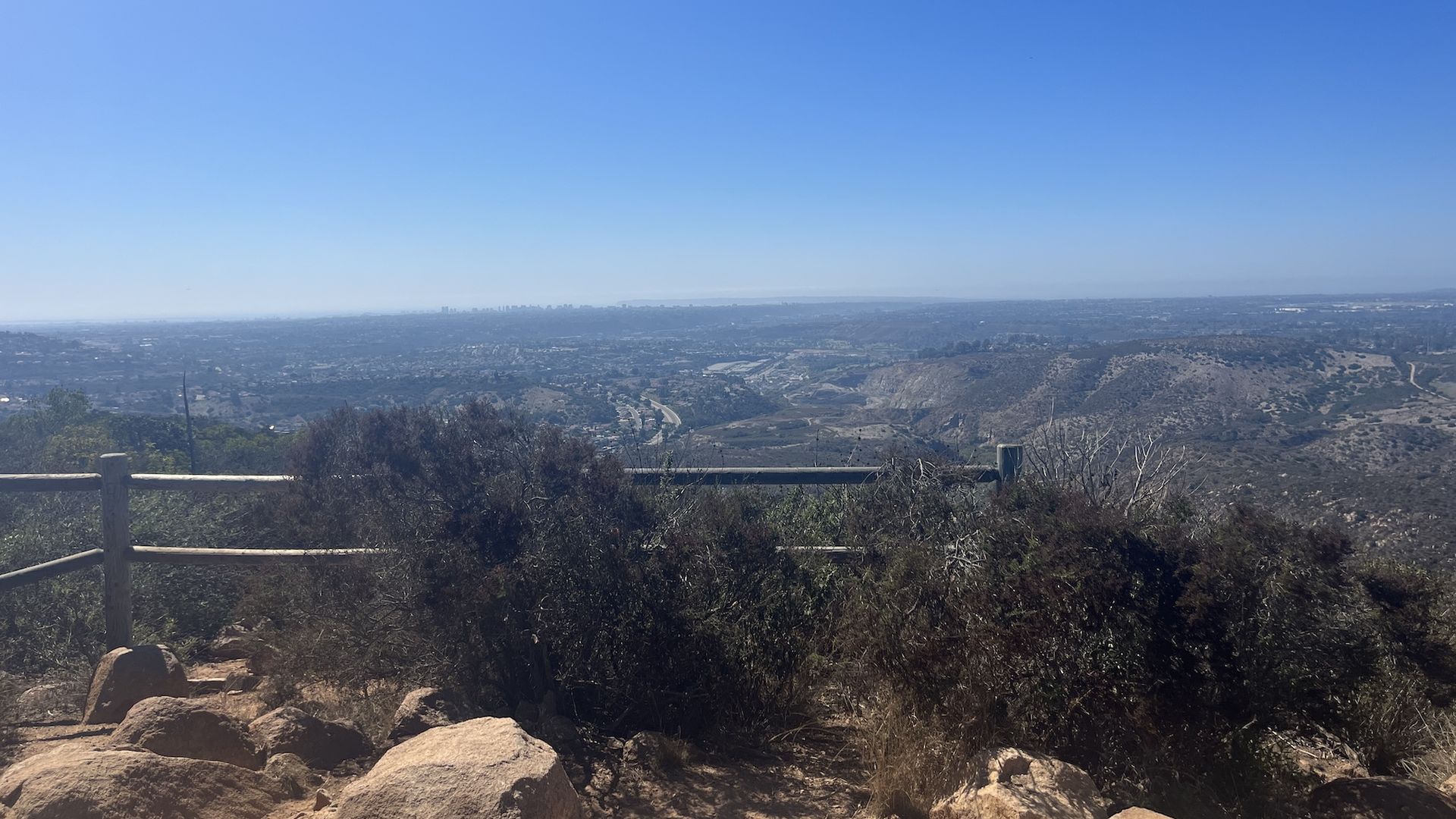 A lookout spot on a mountain overlooking trails with downtown San Siego in the distance. 