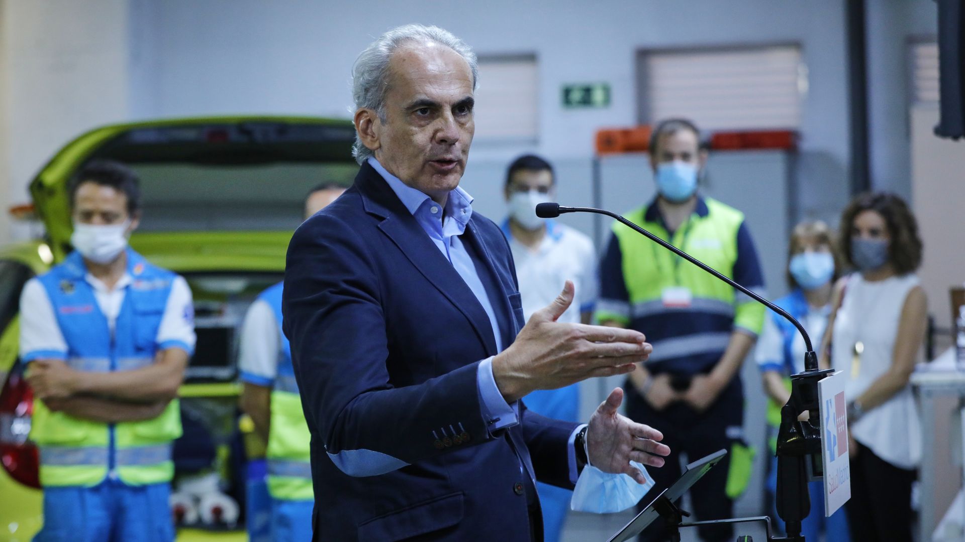 Spain's health councillor stands and speaks in front of a microphone