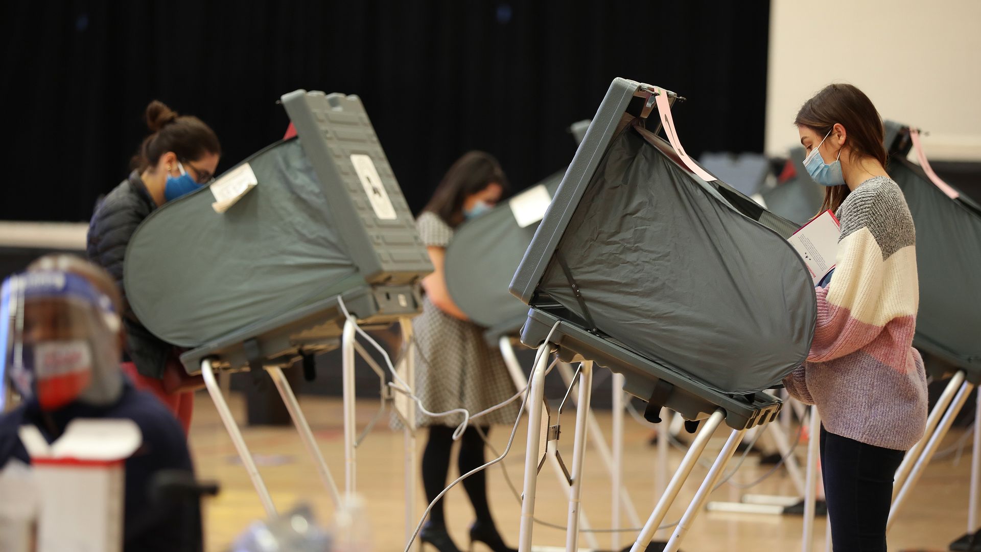 Photo of multiple people standing at polling booths