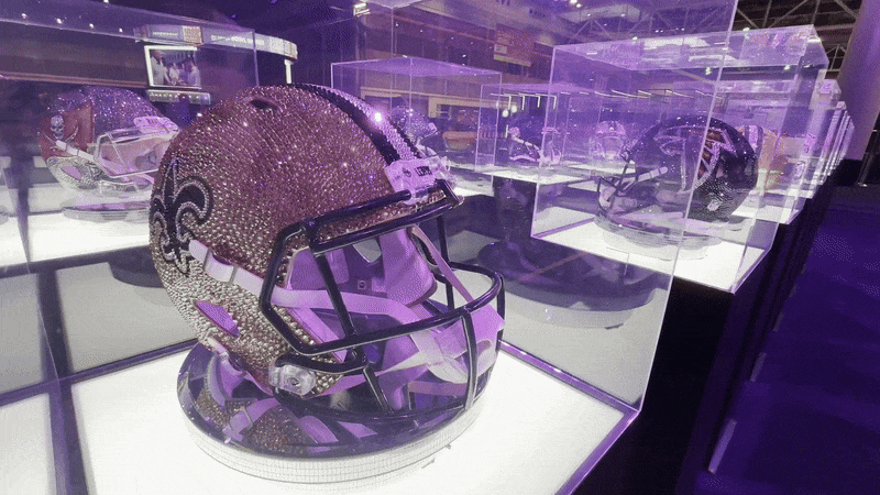 A rhinestone-encrusted Saints helmet rotates in a glass case.