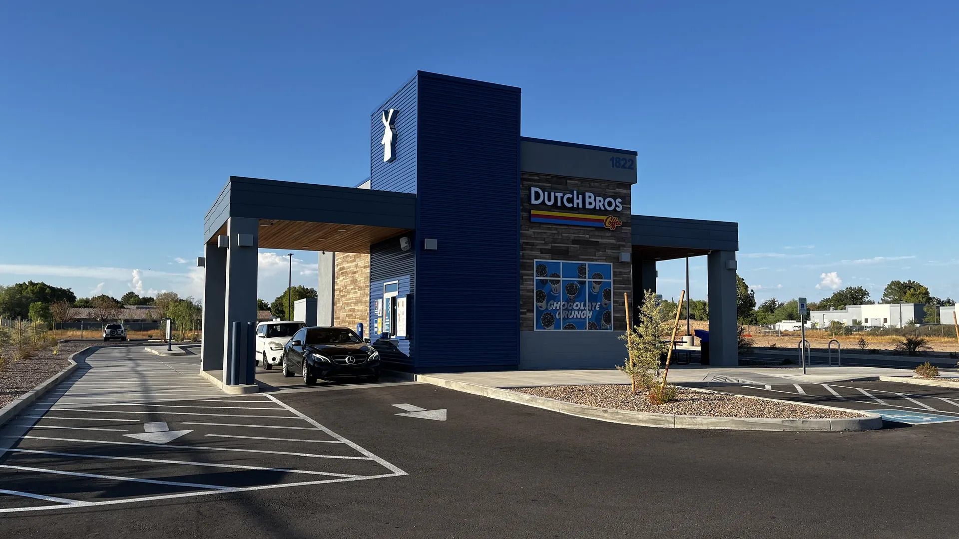 A blue building with two drive throughs and the words Dutch Bros on the front. 