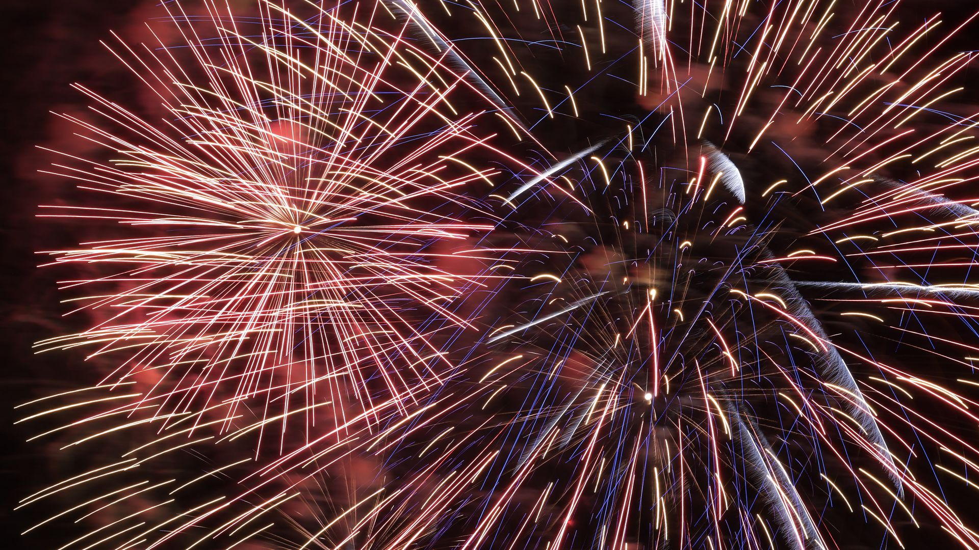 A photo of red and yellow fireworks in the night sky.