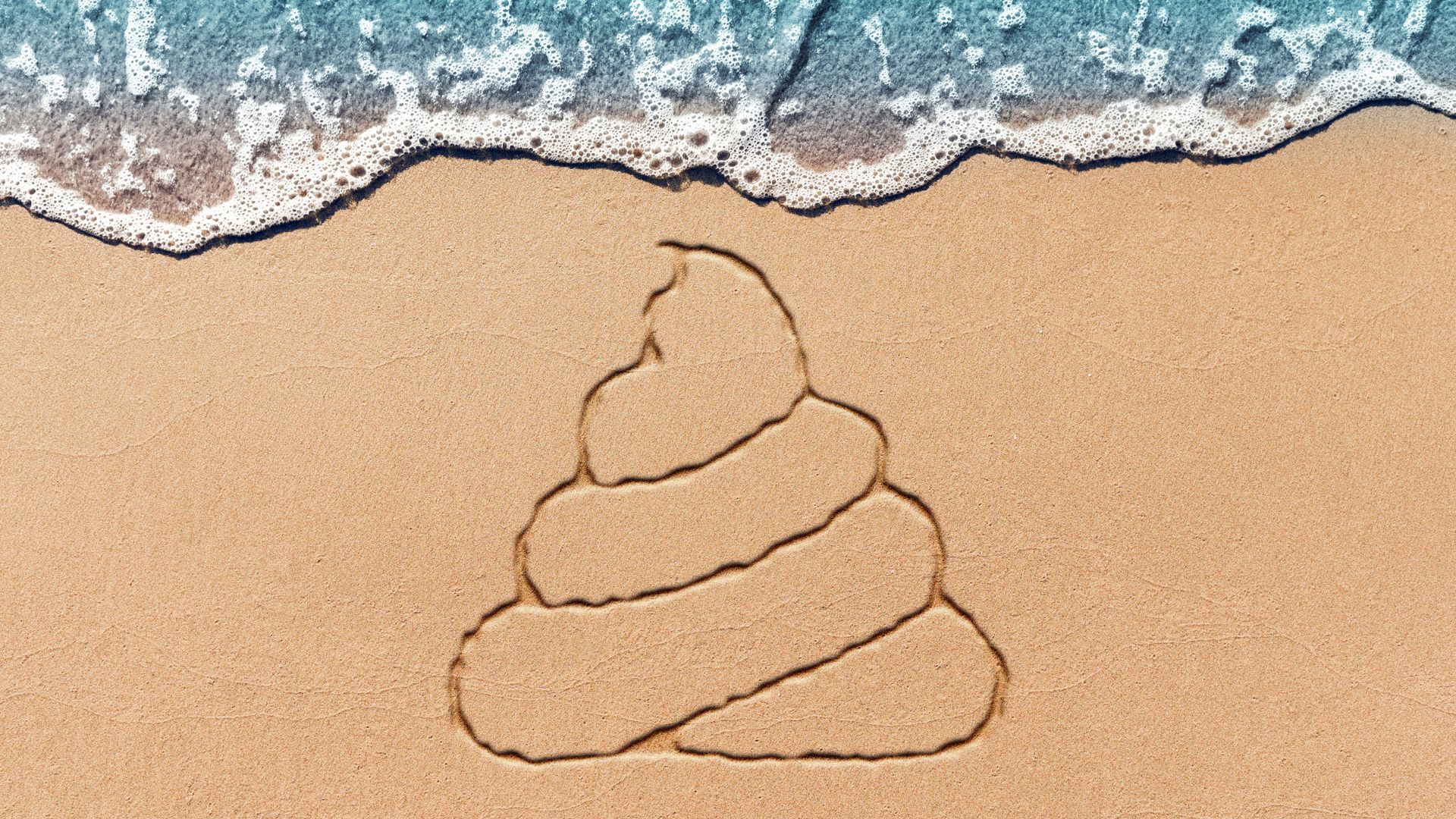Illustration of a poop emoji drawn in the sand. 