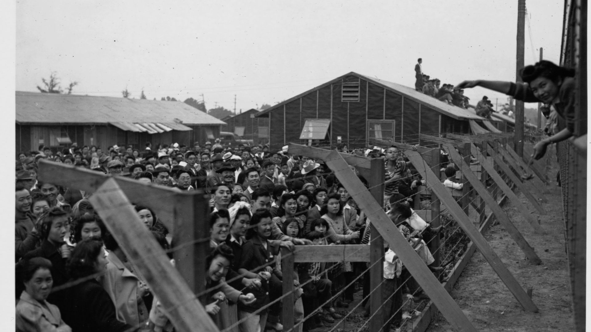 Japanese-American internees wave to friends departing by train from the Santa Anita Assembly Center at Santa Anita Racetrack in Arcadia, California, 1942. 