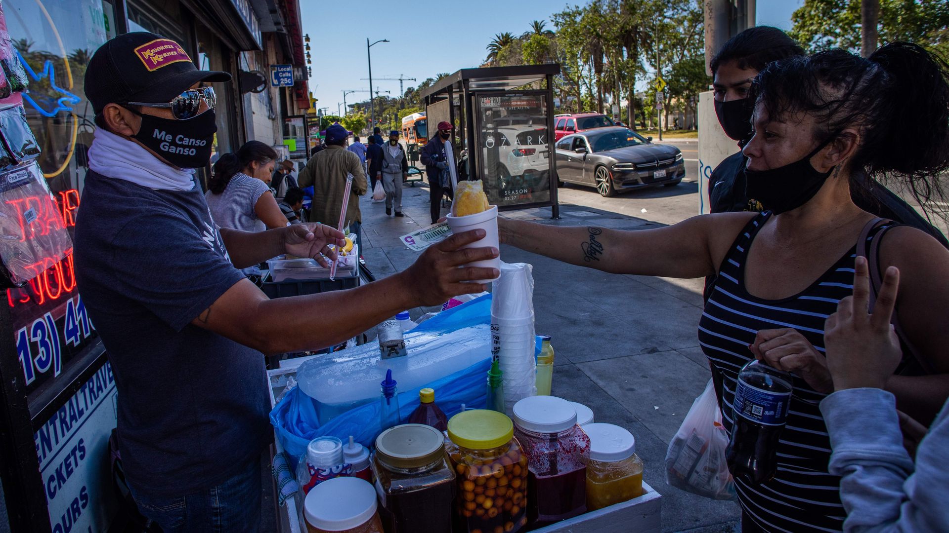 In this image, a woman buys ice cream from a street vendor