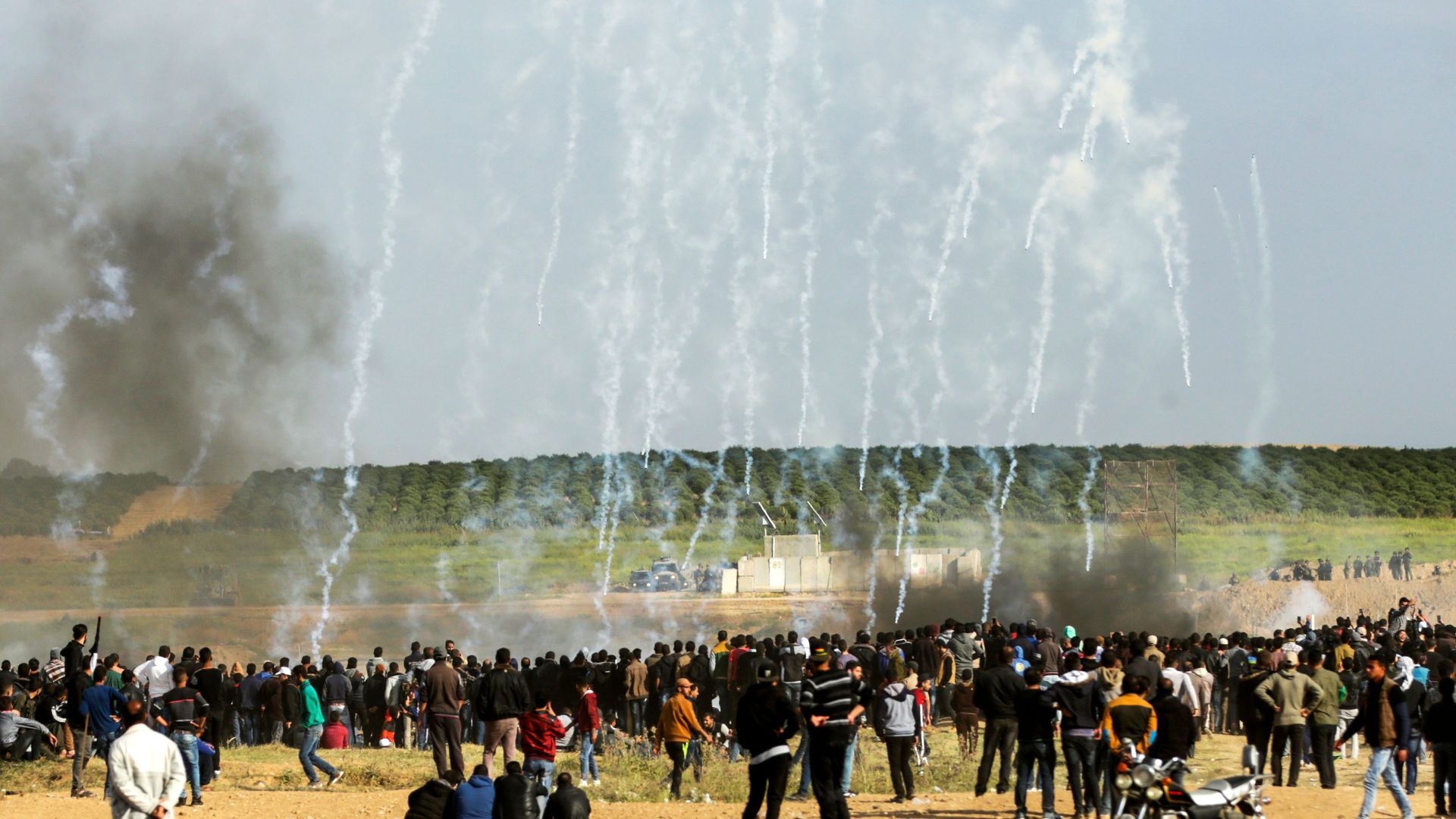 Palestinian protestors run for cover from tear gas fired by Israeli security forces during clashes following a demonstration commemorating Land Day, near the border with Israel