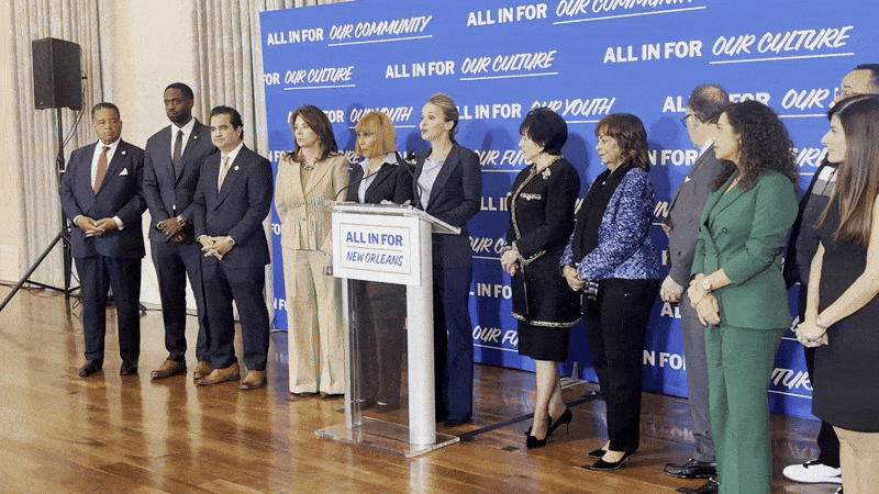 Helena Moreno, Gayle Benson, City Council members and other officials stand in front of a banner that says "all in for our community."
