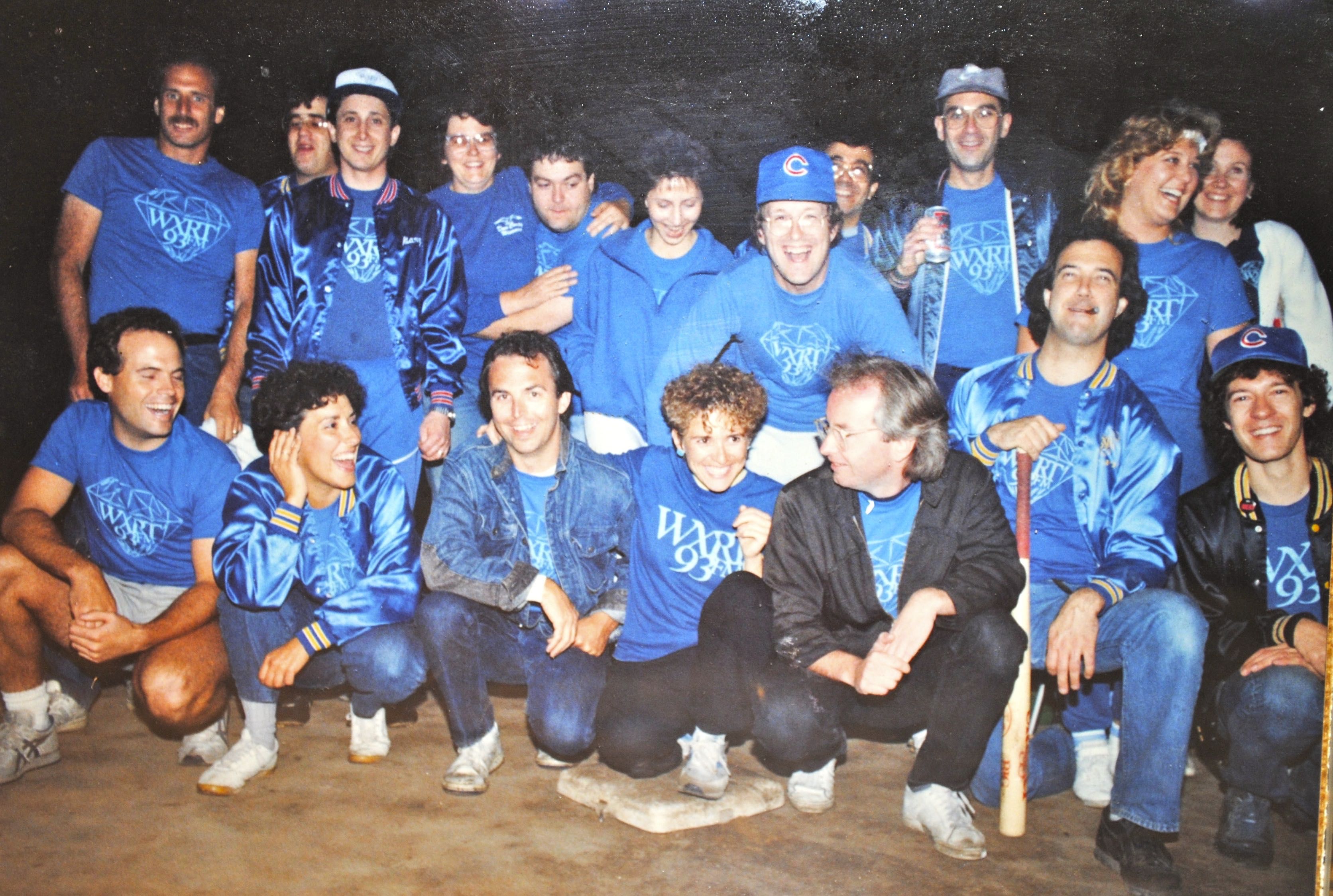 Photo of a softball team posing on a softball diamond. 