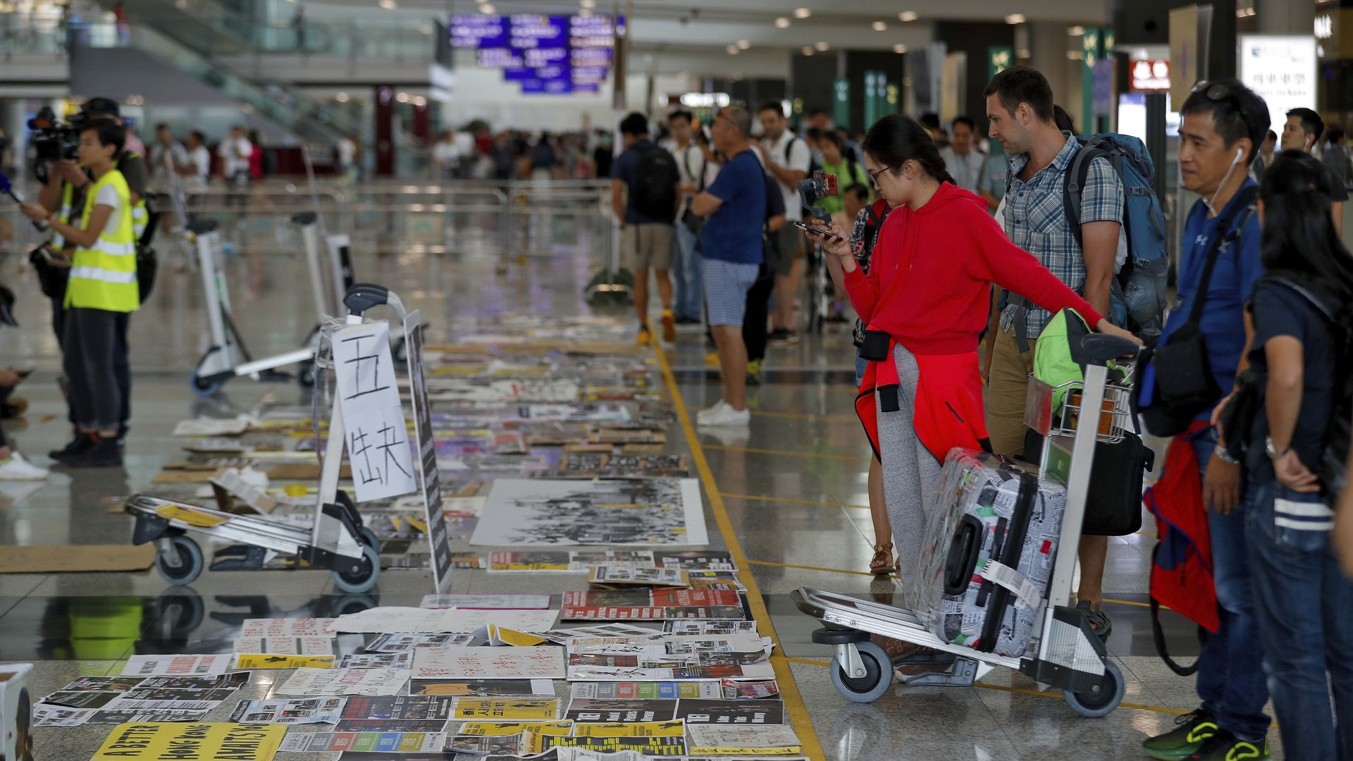 Travellers look at placards and posters placed by protesters at the airport in Hong Kong
