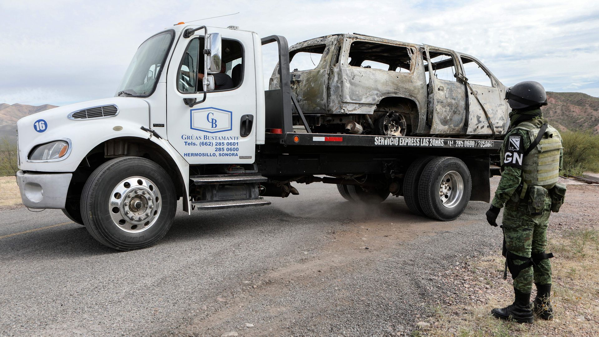 A worker lifts to the tow truck the burnt van where five of the nine members of the Mexican-American LeBaron family were killed, in the Sonora mountain range, Mexico, on November 6
