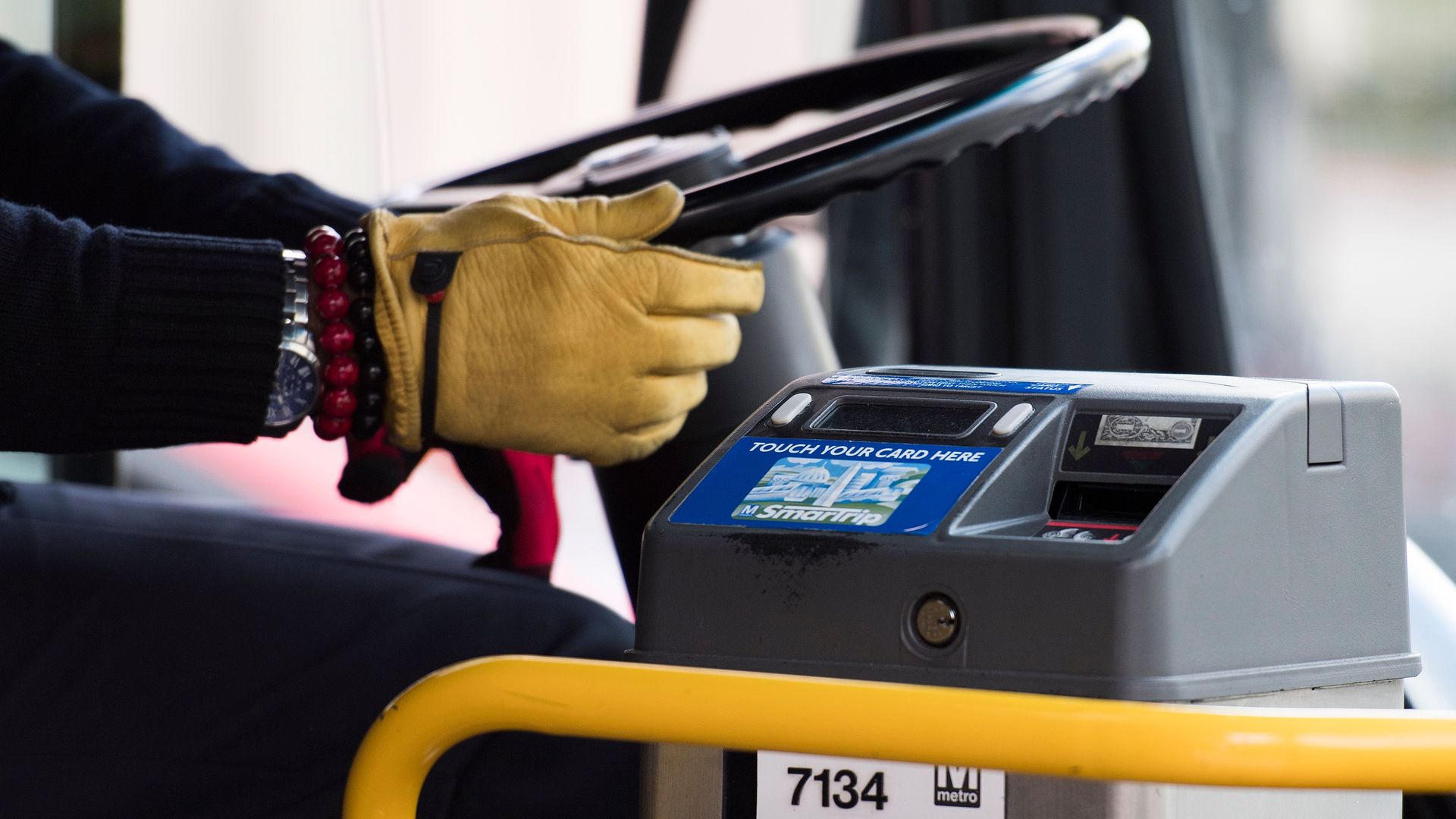 A closeup of a Metrobus operator holding the wheel.