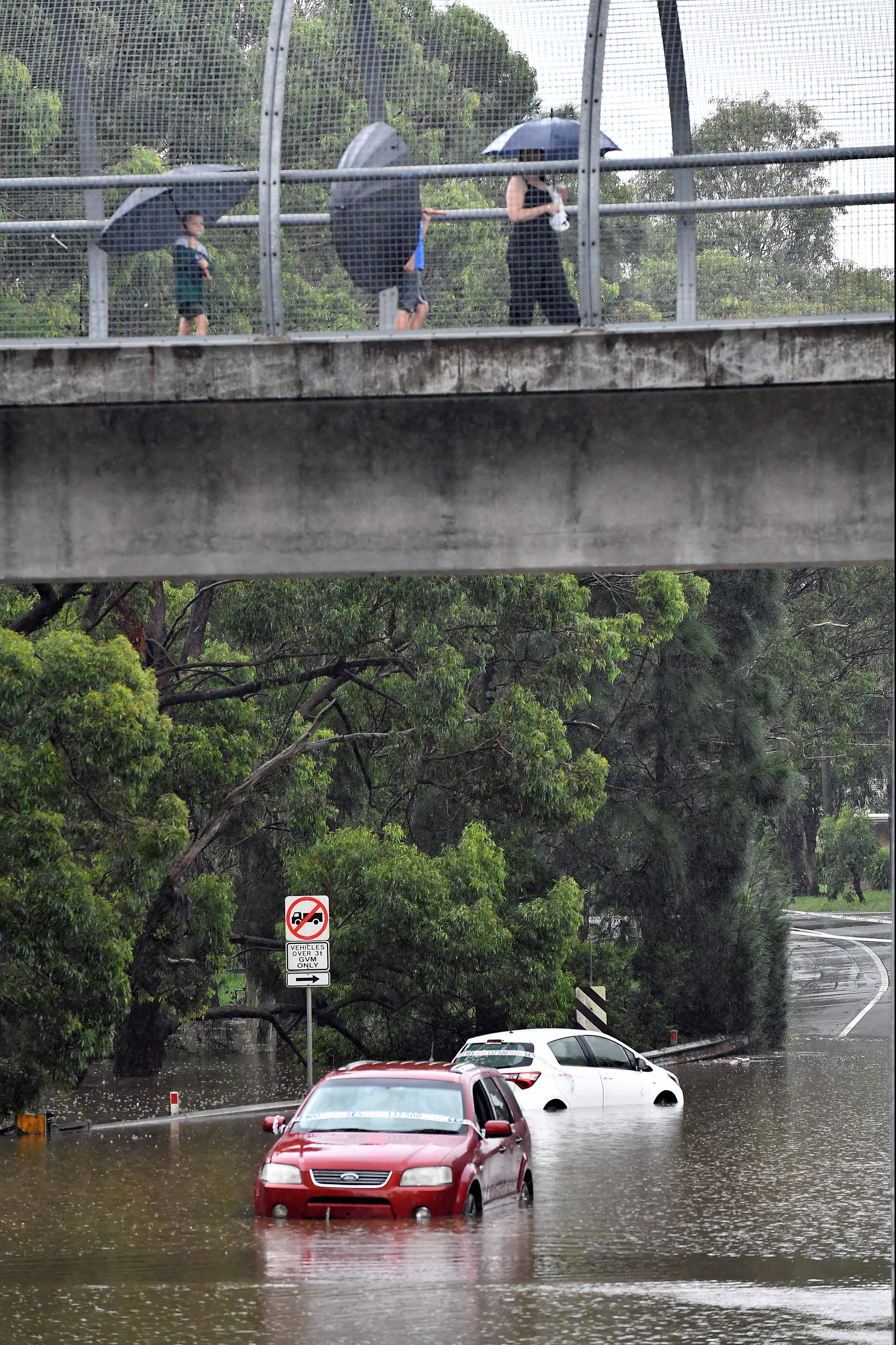 Residents use a pedestrian bridge as floodwaters reach residential areas in southwestern  Sydney on March 8.