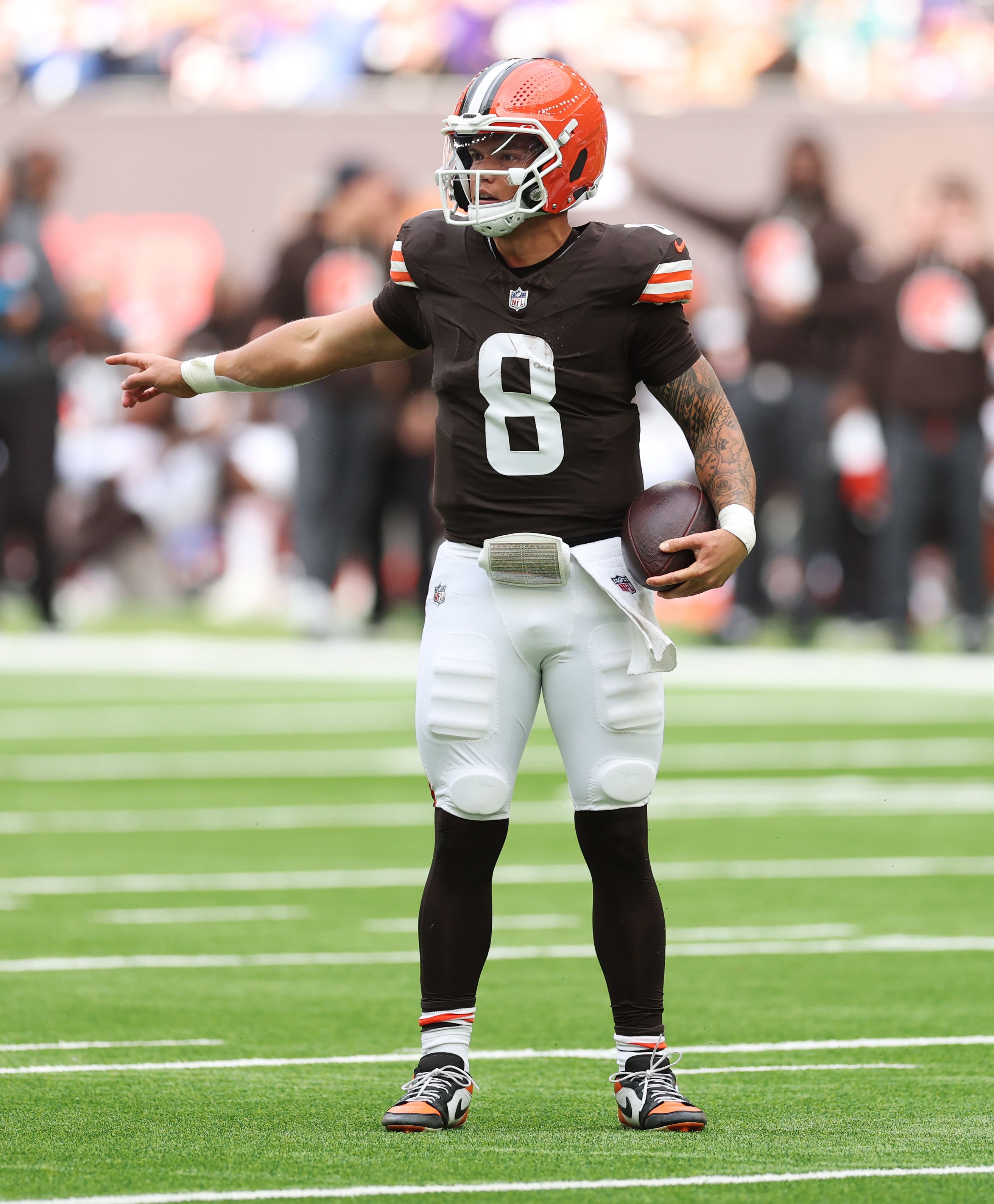 Browns quarterback Dillon Gabriel, No. 8, holds a football on the field pointing to his right. 