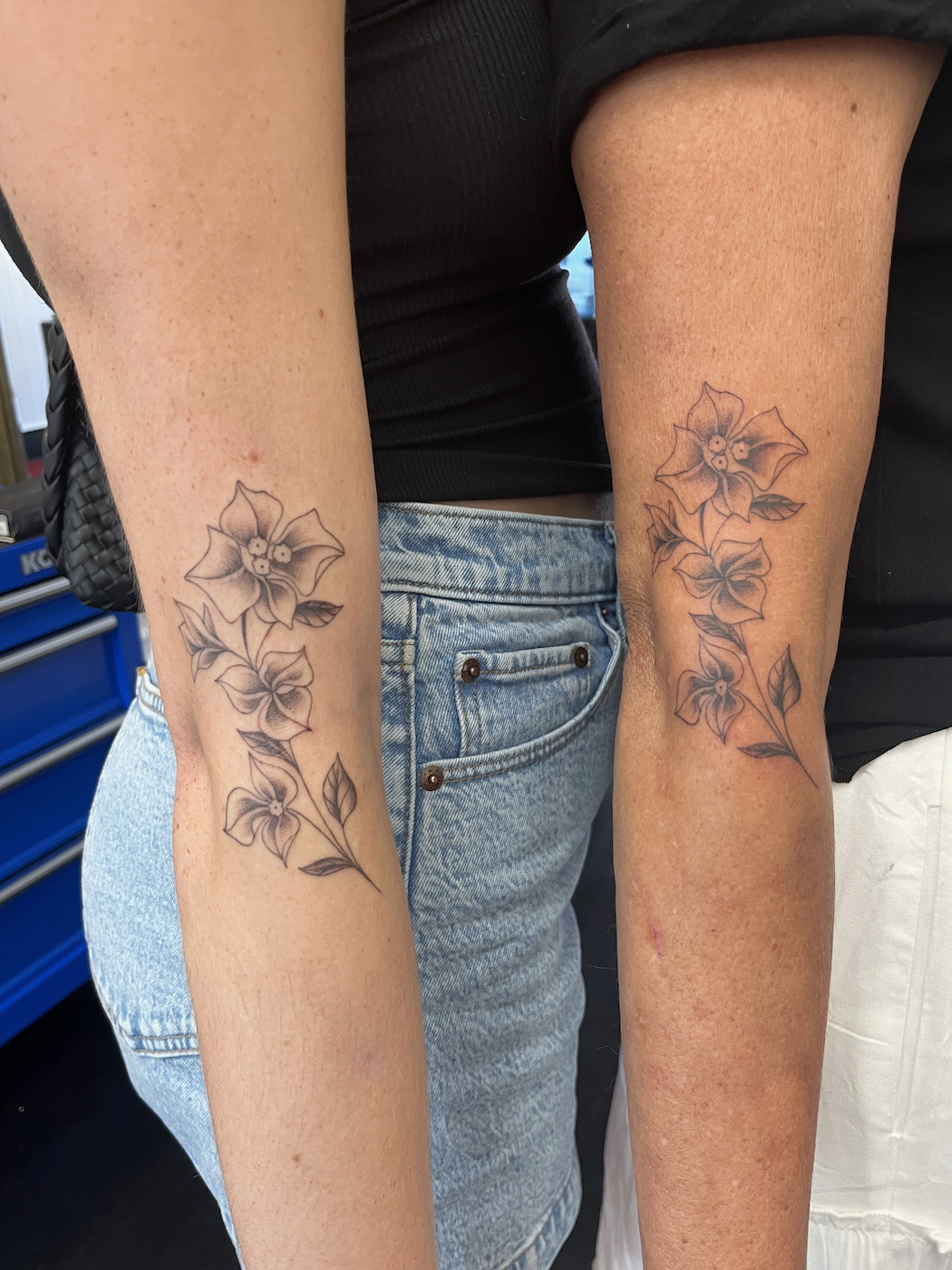 Two arms with floral tattoos
