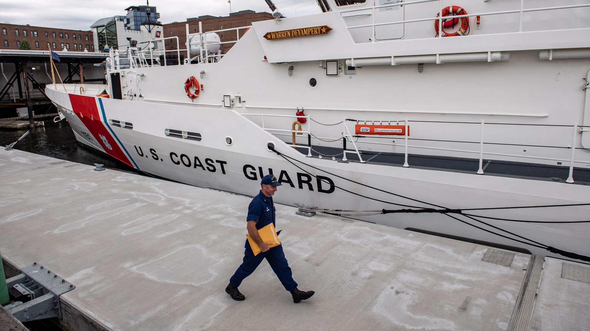 A person walking alongside a U.S. Coast Guard vessel in Boston on June 20.