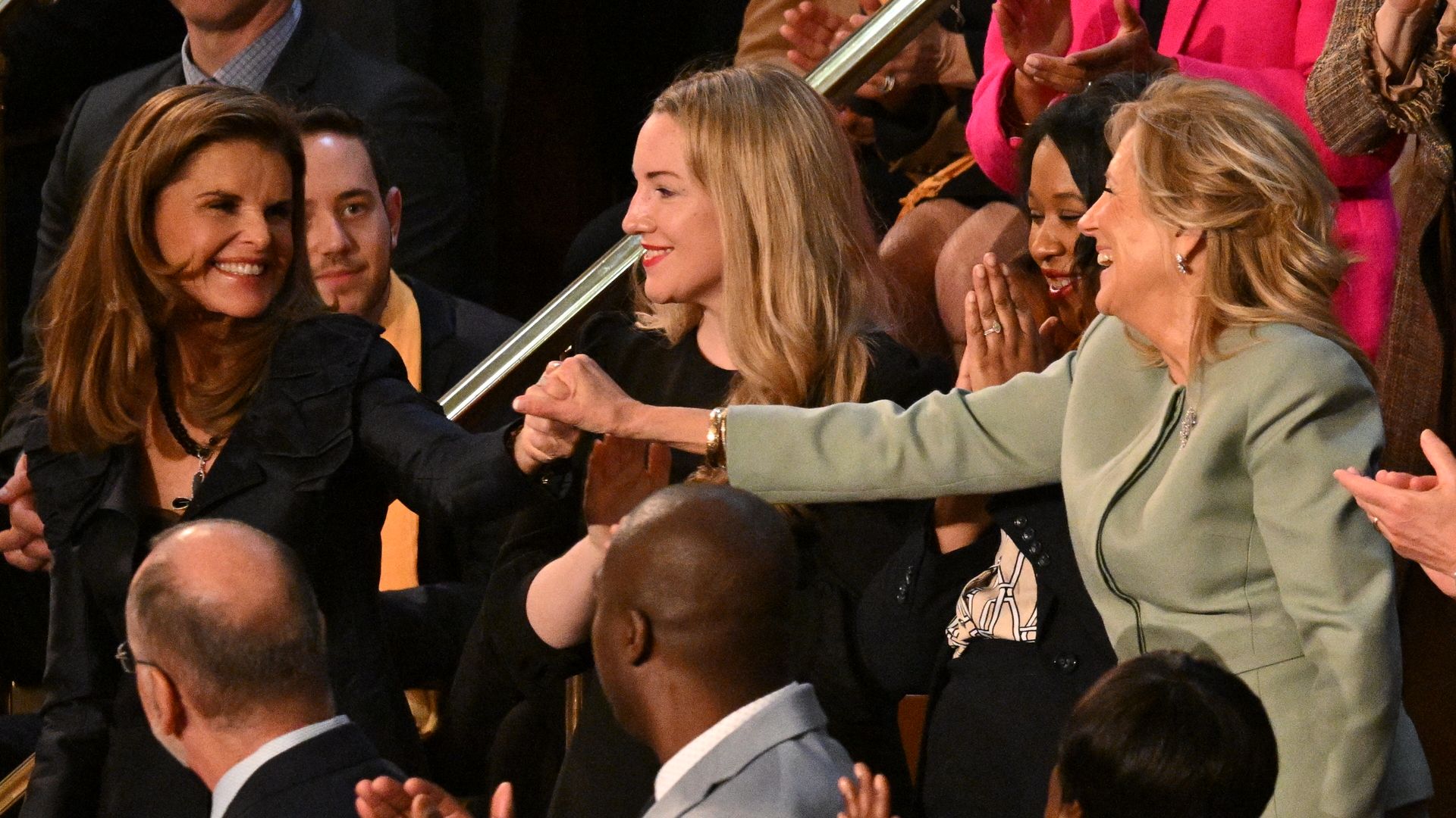 Two women shaking hands with one woman in the middle