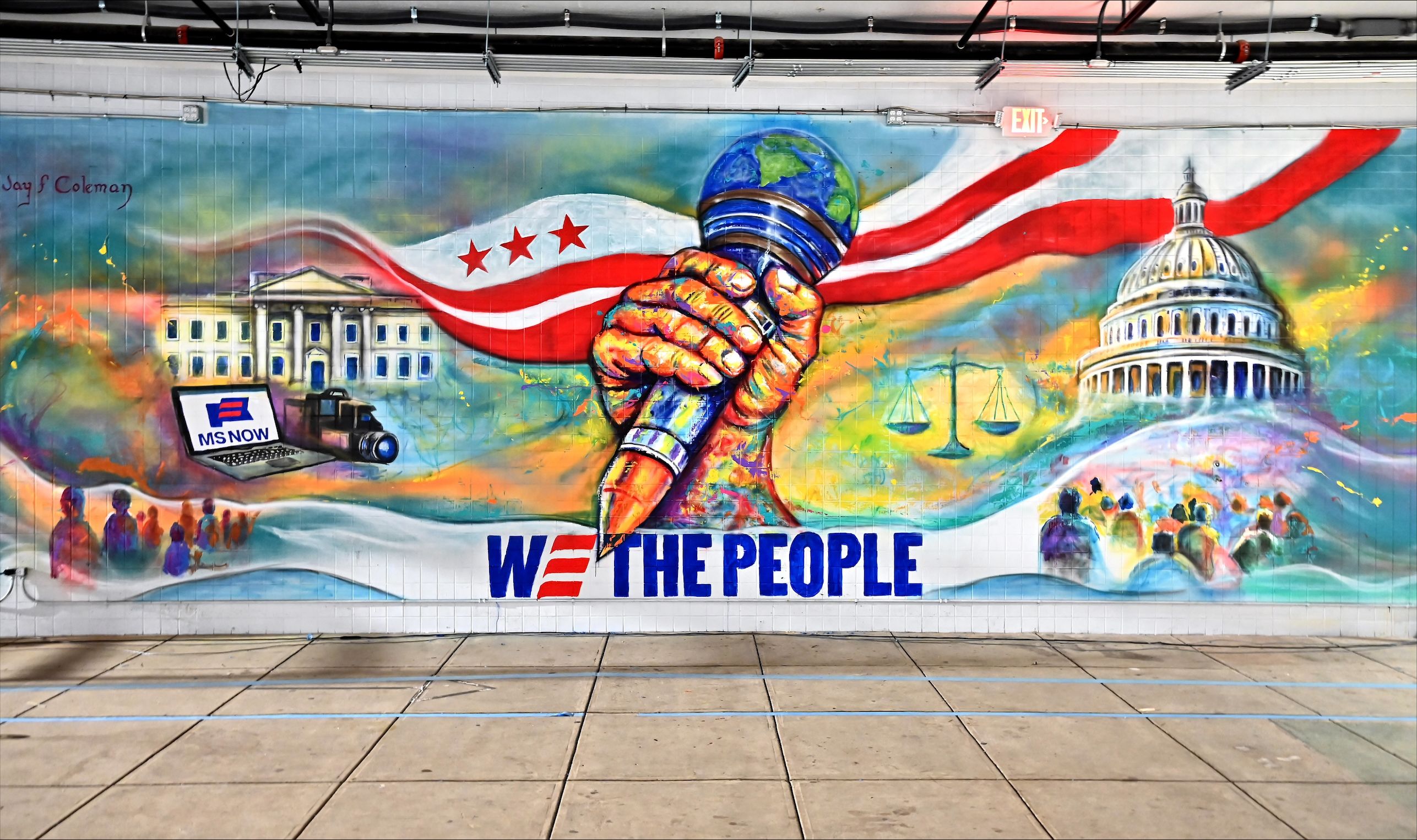 Colorful mural featuring a giant fist gripping a globe as red and white stripes wave behind; Capitol dome on the right, scales of justice, a laptop labeled "MS NOW", and "WE THE PEOPLE" across the bottom.