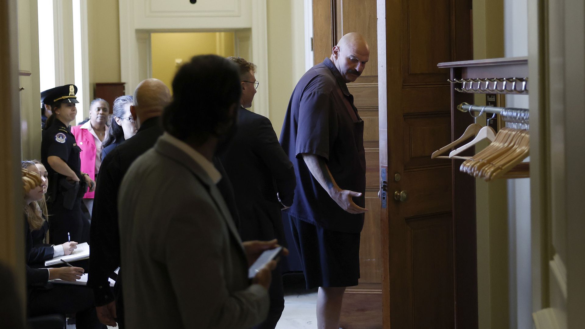 Pennsylvania Senator John Fetterman, wearing a blue short-sleeved shirt and short pants, is shown in a hallway in the U.S. Capitol.