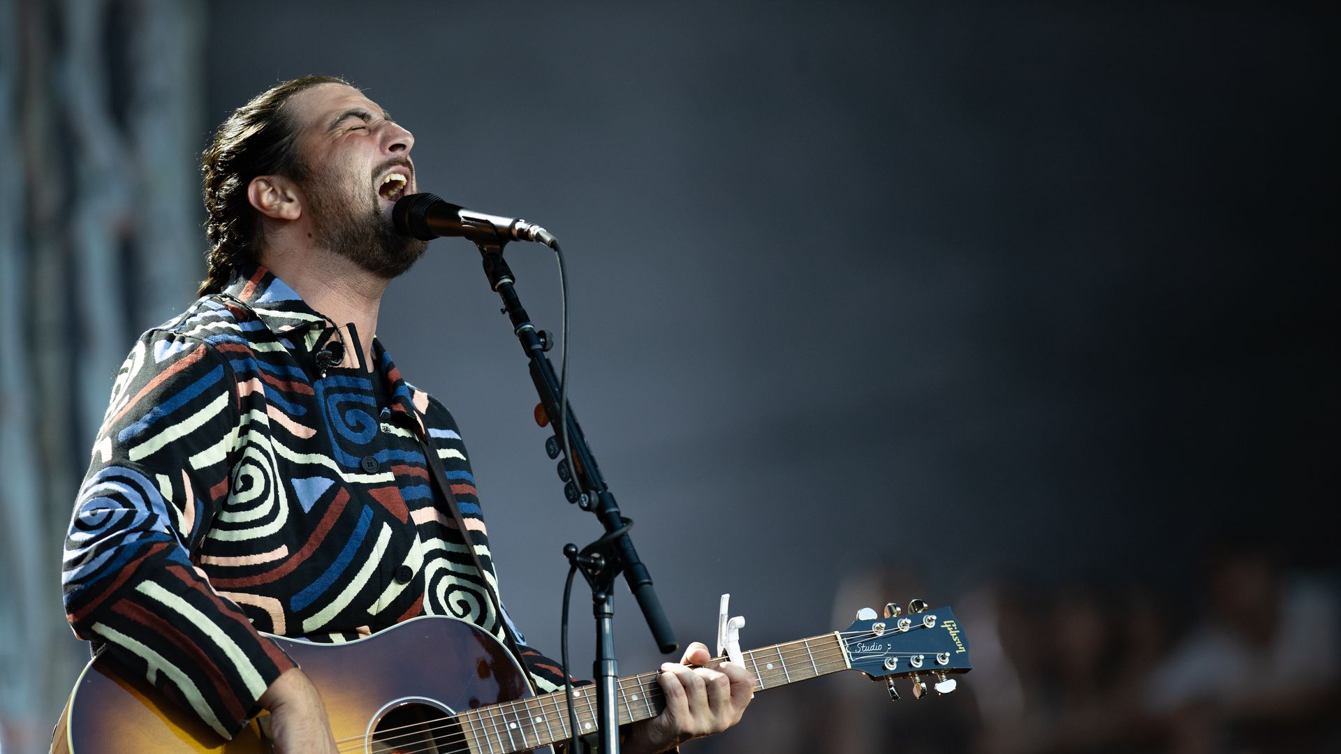 Noah Kahan sings into a microphone