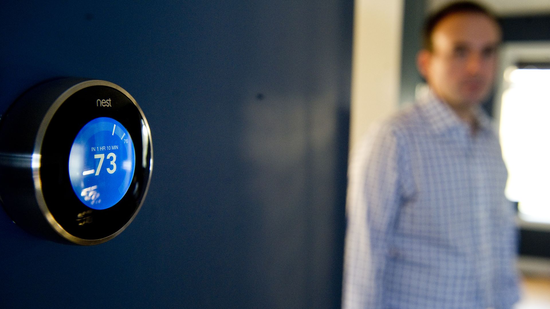 Nick DeLena adjusts his thermostat from Nest Labs in his home.