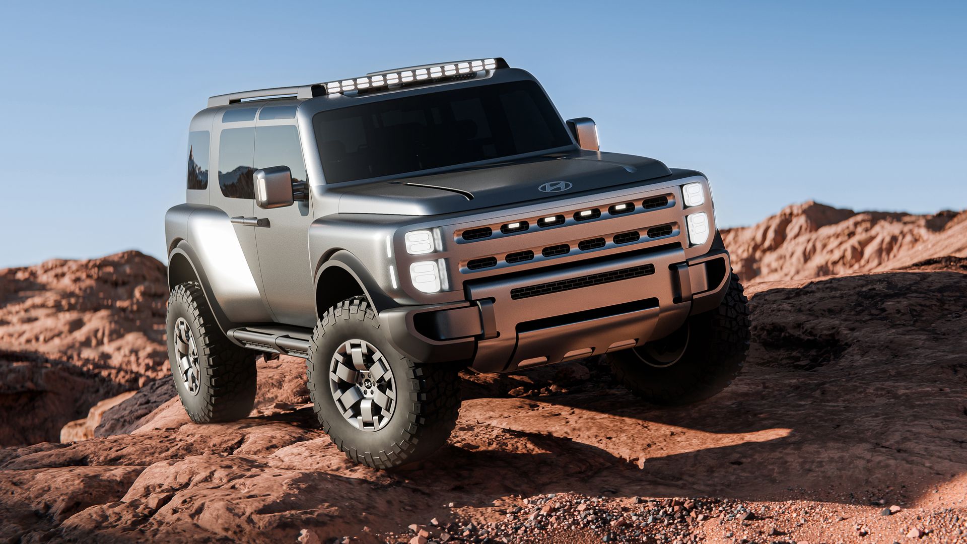 Silver off-road SUV with a roof light bar navigates rocky desert terrain beneath a clear blue sky; oversized tires, raised suspension, and a rugged bumper emphasize rugged adventure.