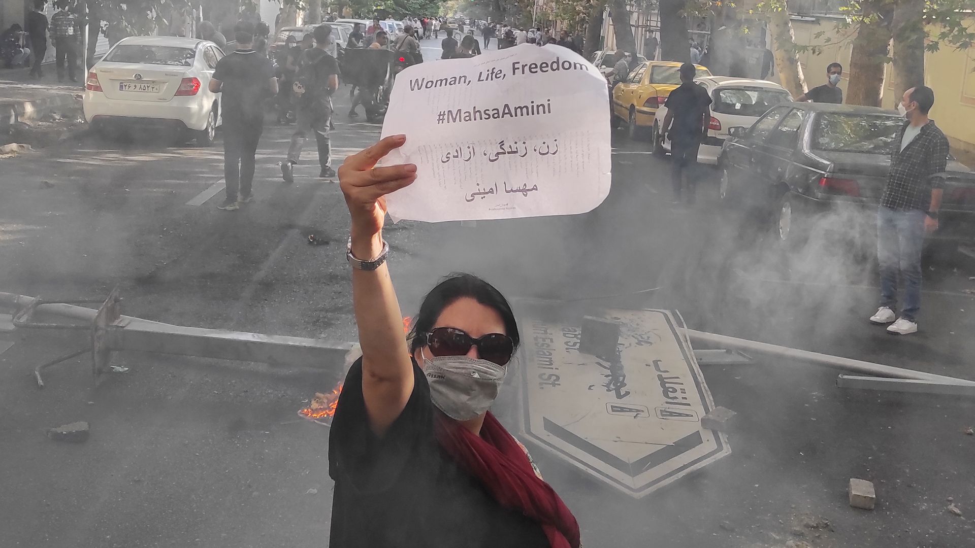 A protester holds up a note reading "Woman, Life, Freedom, #MahsaAmini" while marching down a street on October 1, 2022 in Tehran, Iran