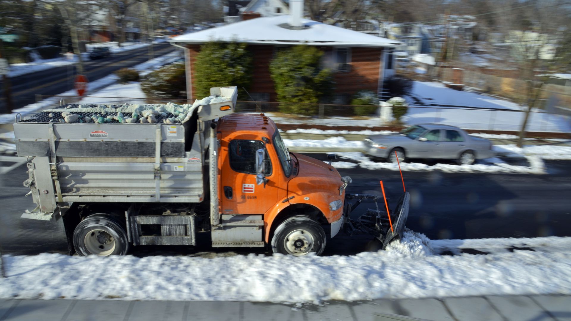 A D.C. snow plow truck driving on a residential block